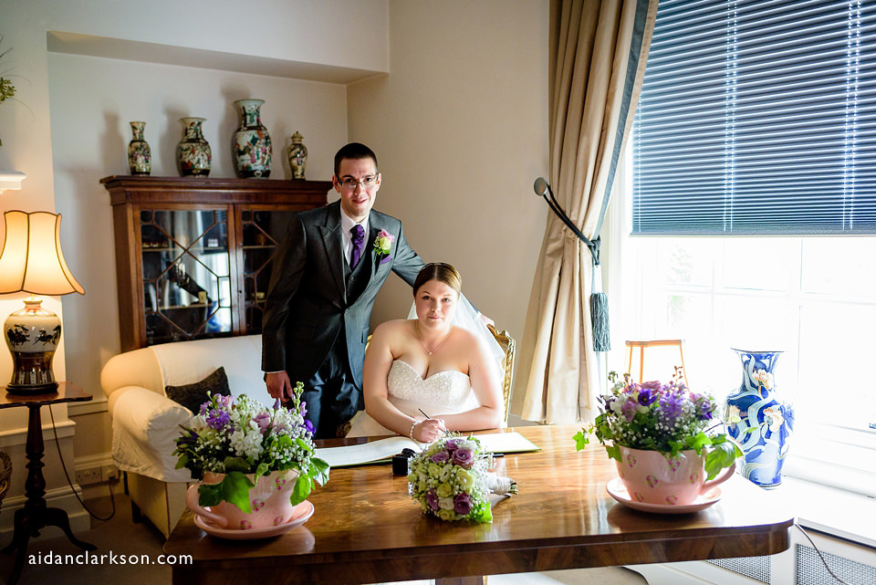 a photo of the couple signing the register at hemswell court wedding venue
