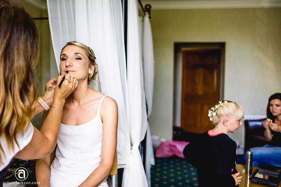 A bride getting her makeup done in a hotel room before her wedding at Kenwick Park.