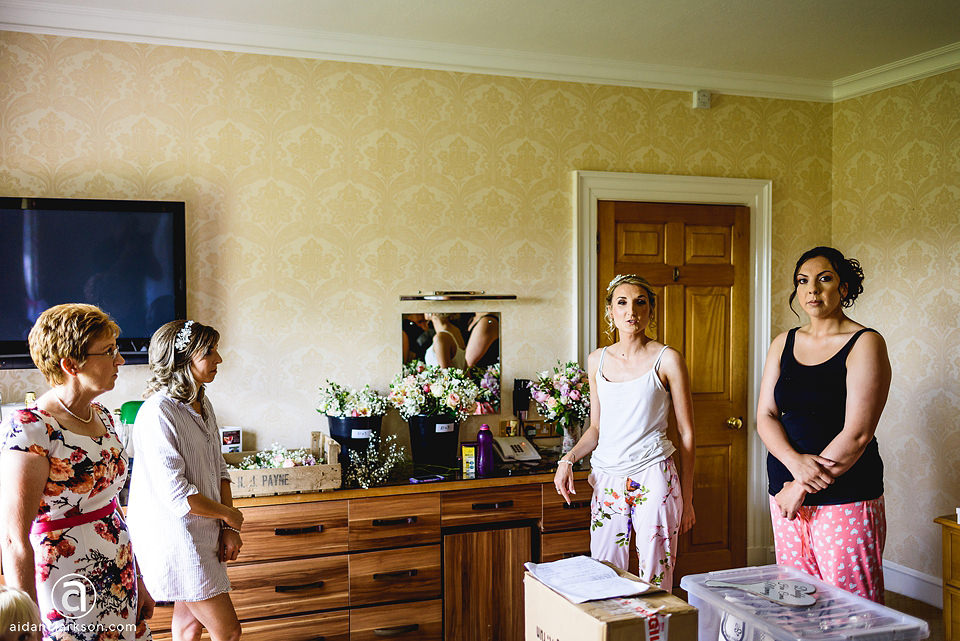 A group of women standing in a room at Kenwick Park, during a wedding, with a tv.