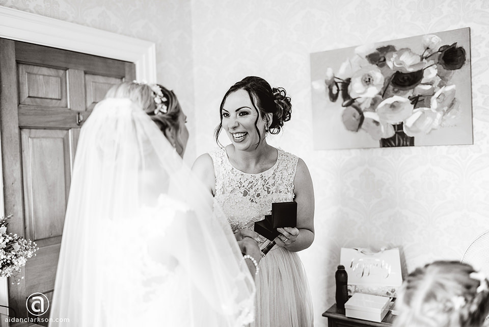 A bride smiles at her bridesmaid as she gets ready for her wedding at Kenwick Park.