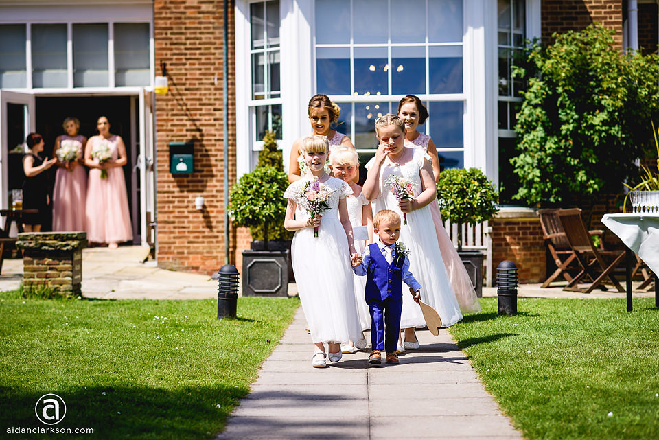 A group of bridesmaids walking down the path of Kenwick Park, in front of a wedding house.