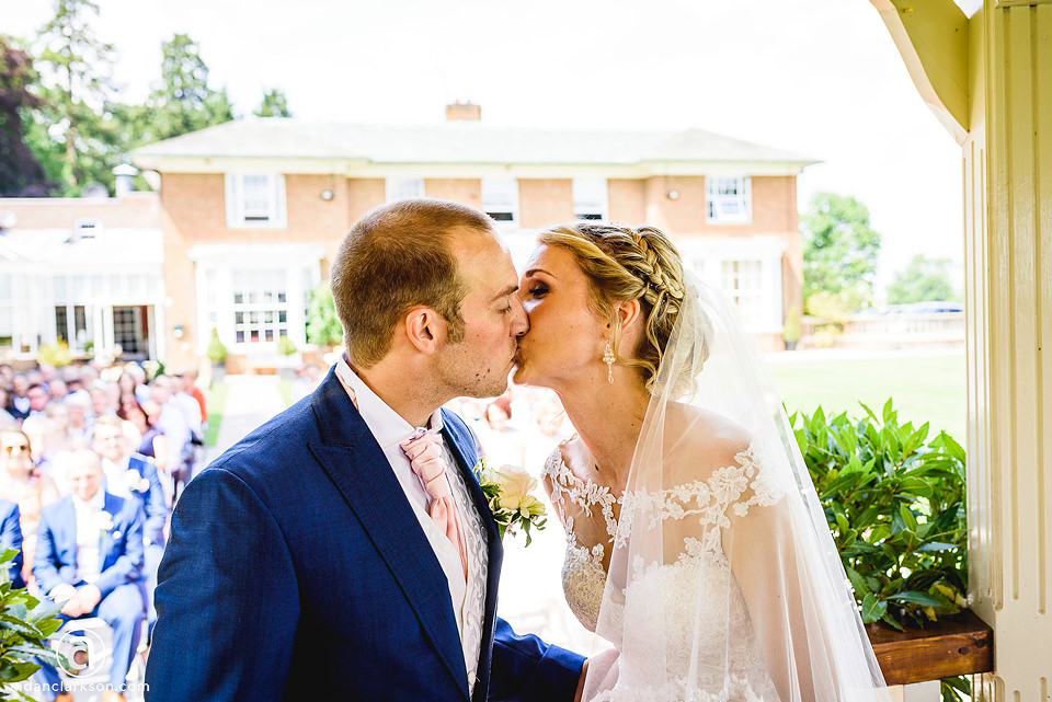 A wedding couple kissing in front of a house at Kenwick Park.