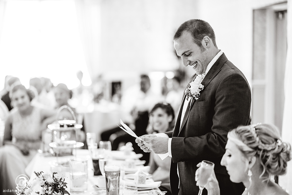 Black and white photo of a man reading a speech at a wedding. The photo was taken at Kenwick Park.