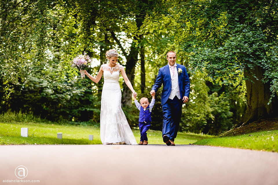 A wedding couple walking down the enchanting path at Kenwick Park, surrounded by the serene woods.