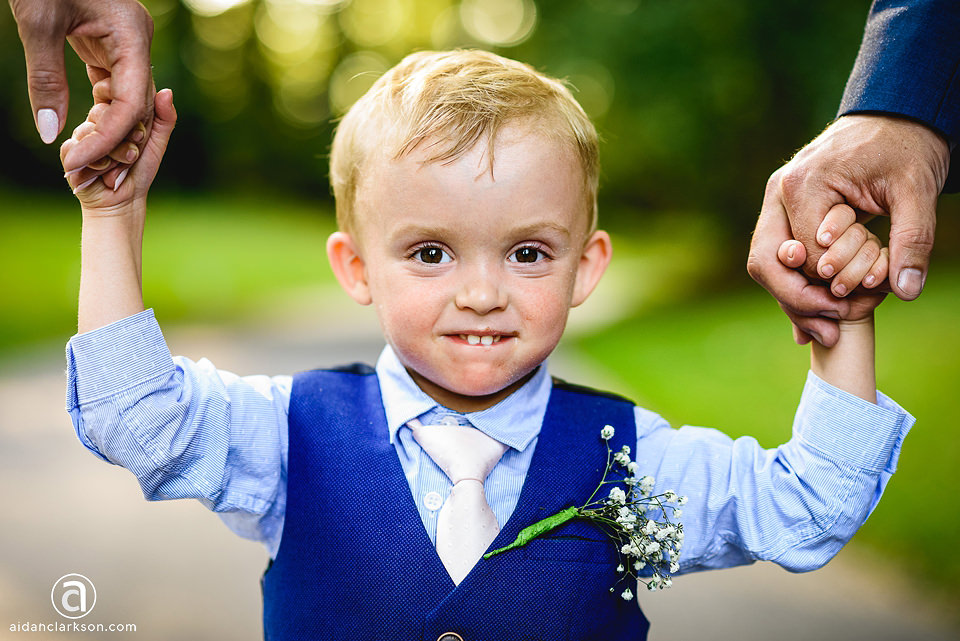 A little boy is holding his hands up in the air at the Kenwick Park wedding.