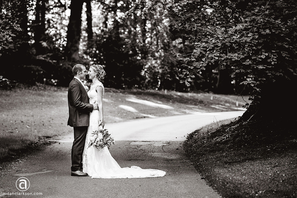 A bride and groom standing on a path in Kenwick Park, during their wedding.