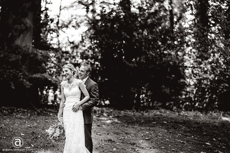 A black and white photo of a bride and groom in the woods during their Kenwick Park wedding.