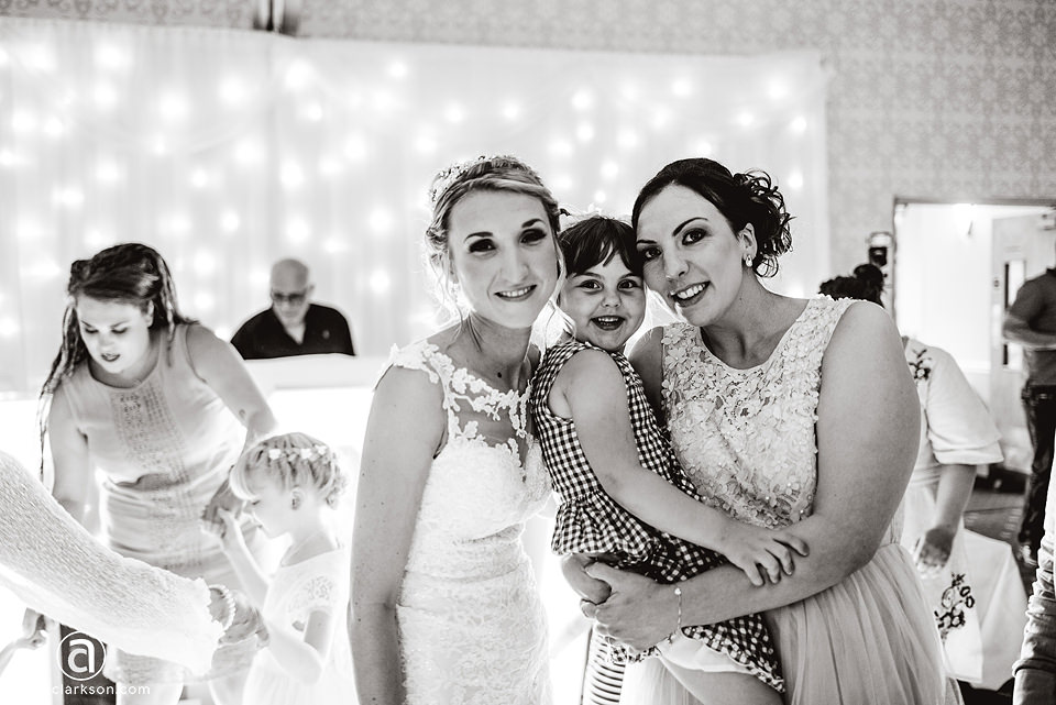 A bride and groom hugging a little girl at their Kenwick Park wedding.