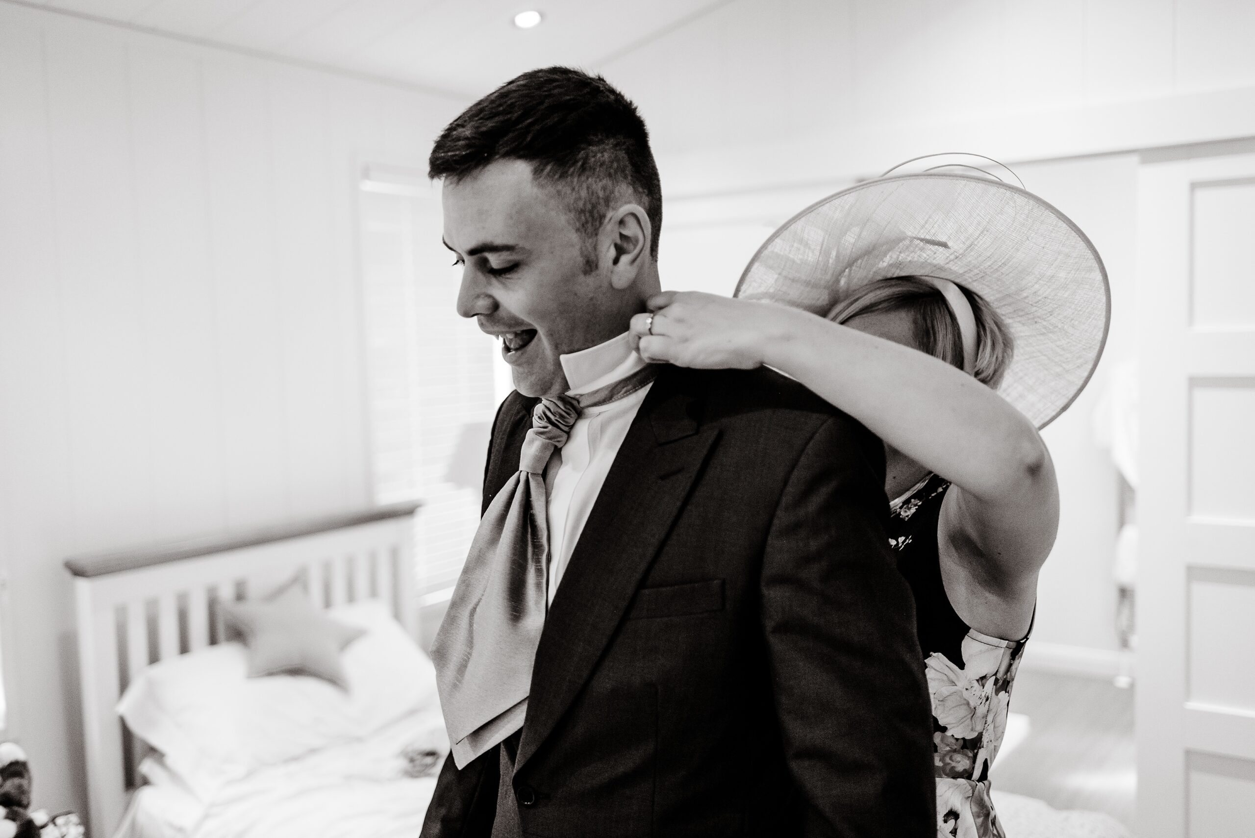 A man in a Laceby Manor suit is adjusting his tie.