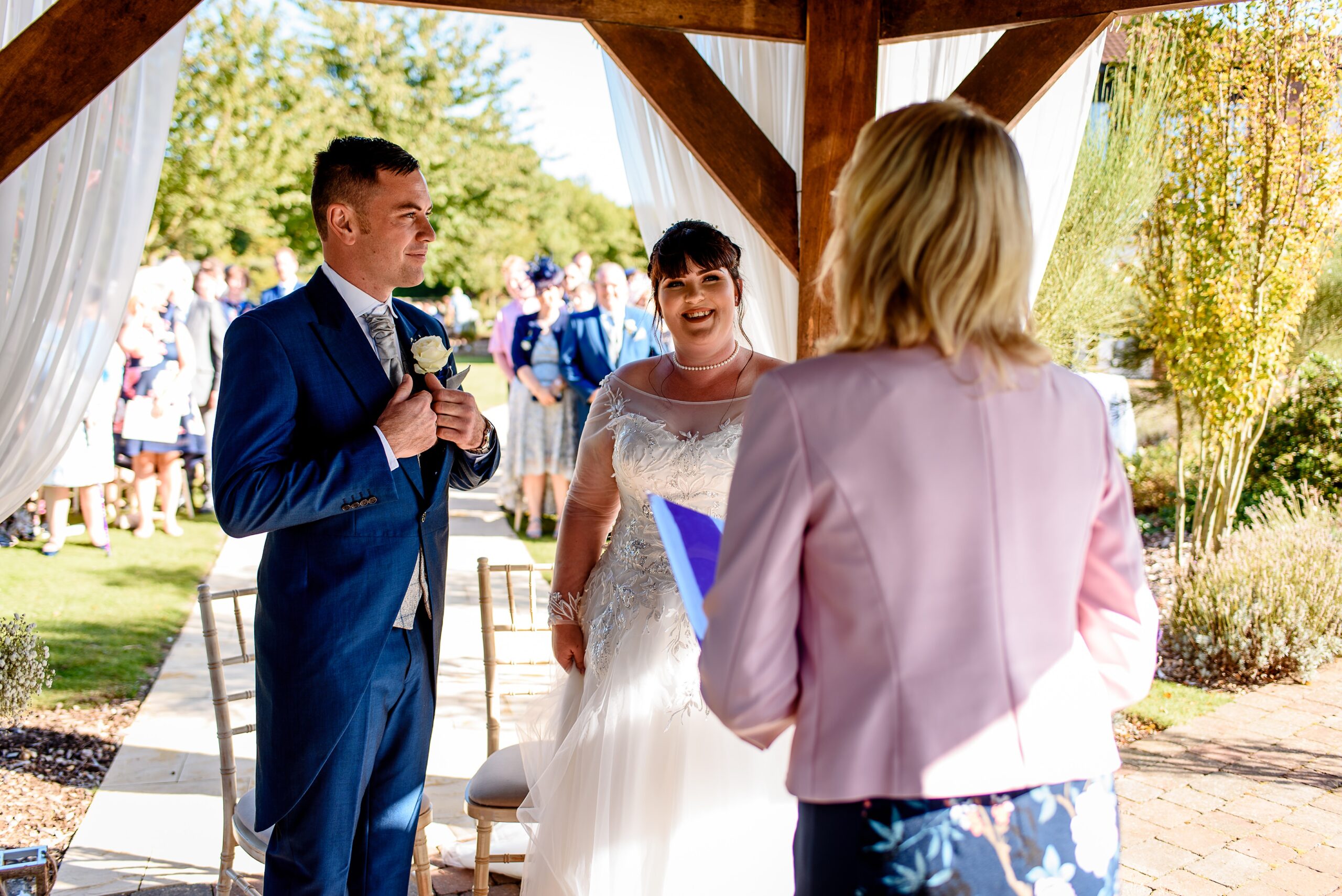 A bride and groom exchange vows at Laceby Manor under a gazebo.