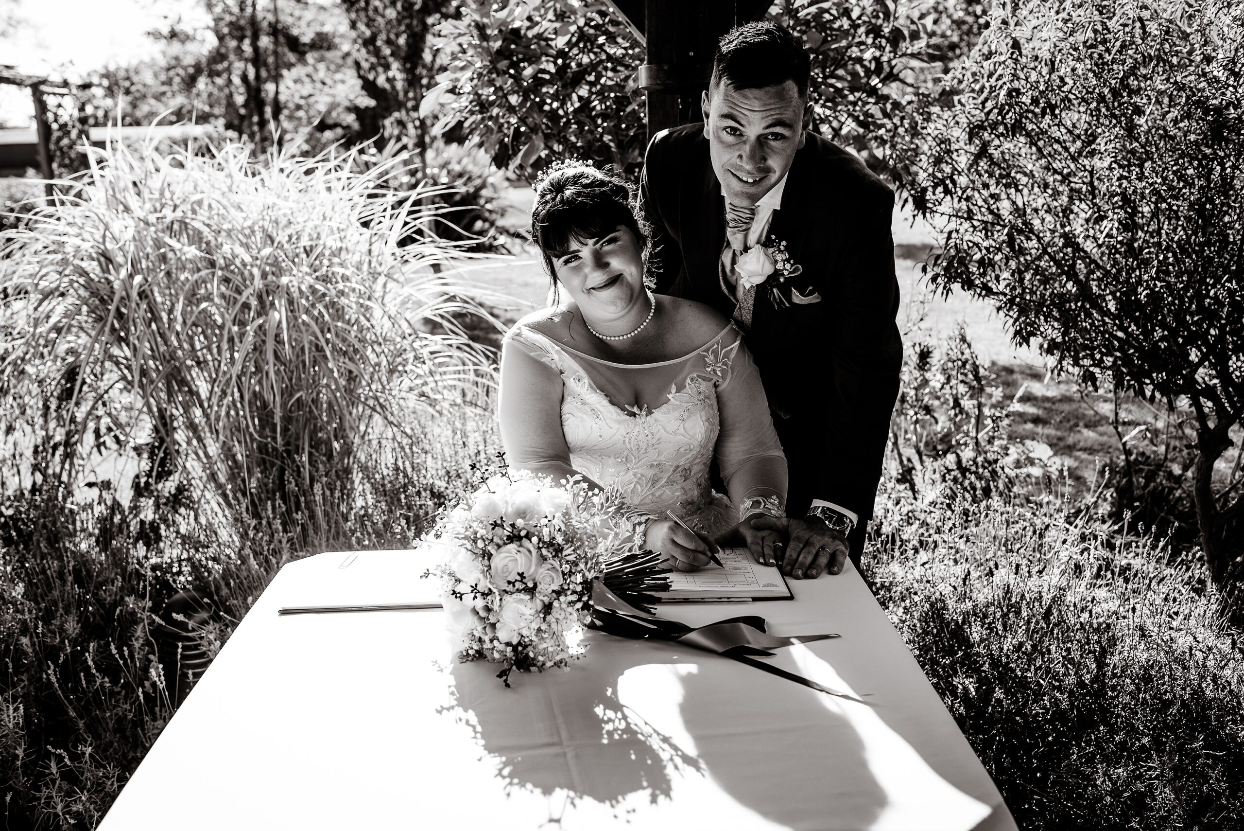 A black and white photo of a bride and groom signing their wedding vows at Laceby Manor.