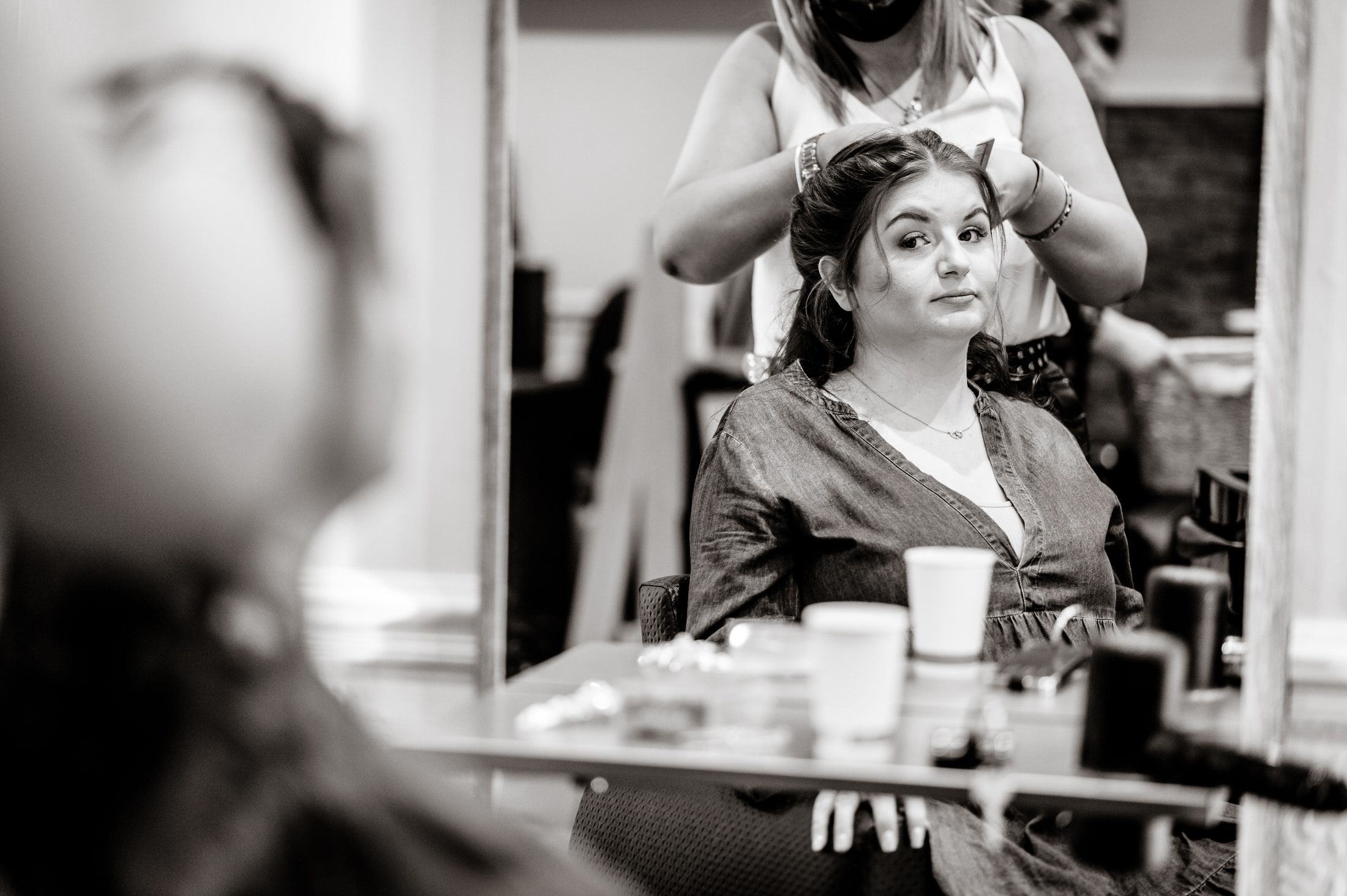 A woman getting her hair done at Brackenborough Hotel for a wedding, in front of a mirror.