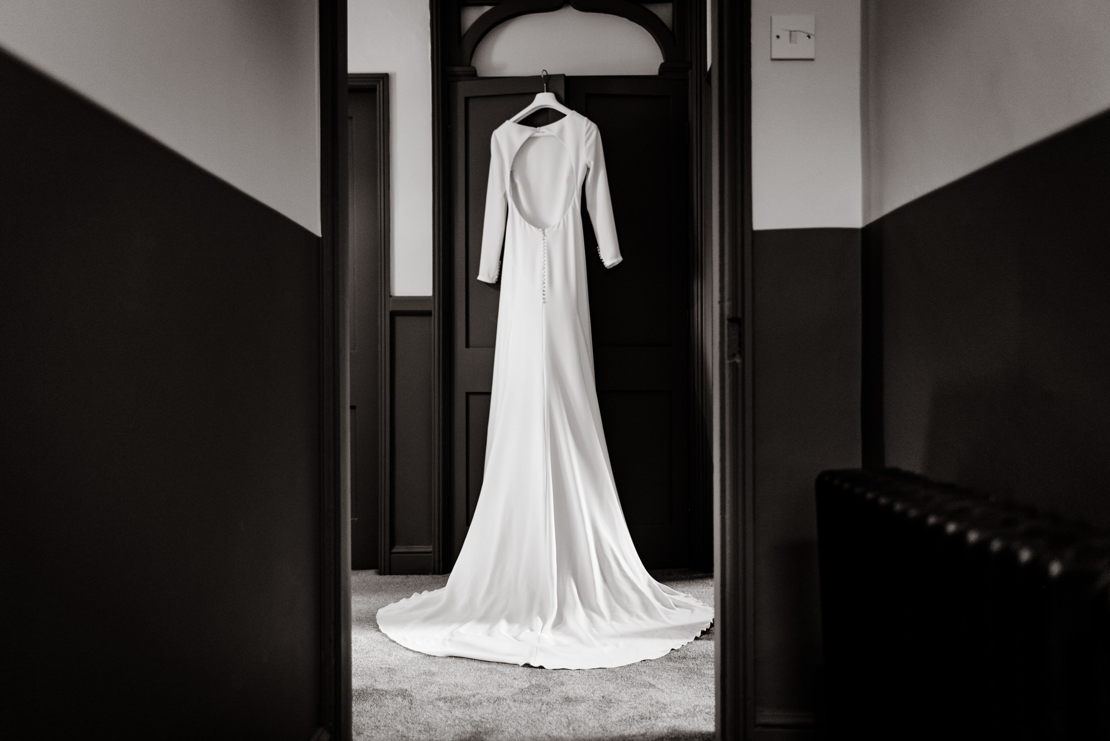 A black and white photo of a wedding dress hanging in the Scrivelsby Walled Garden hallway.