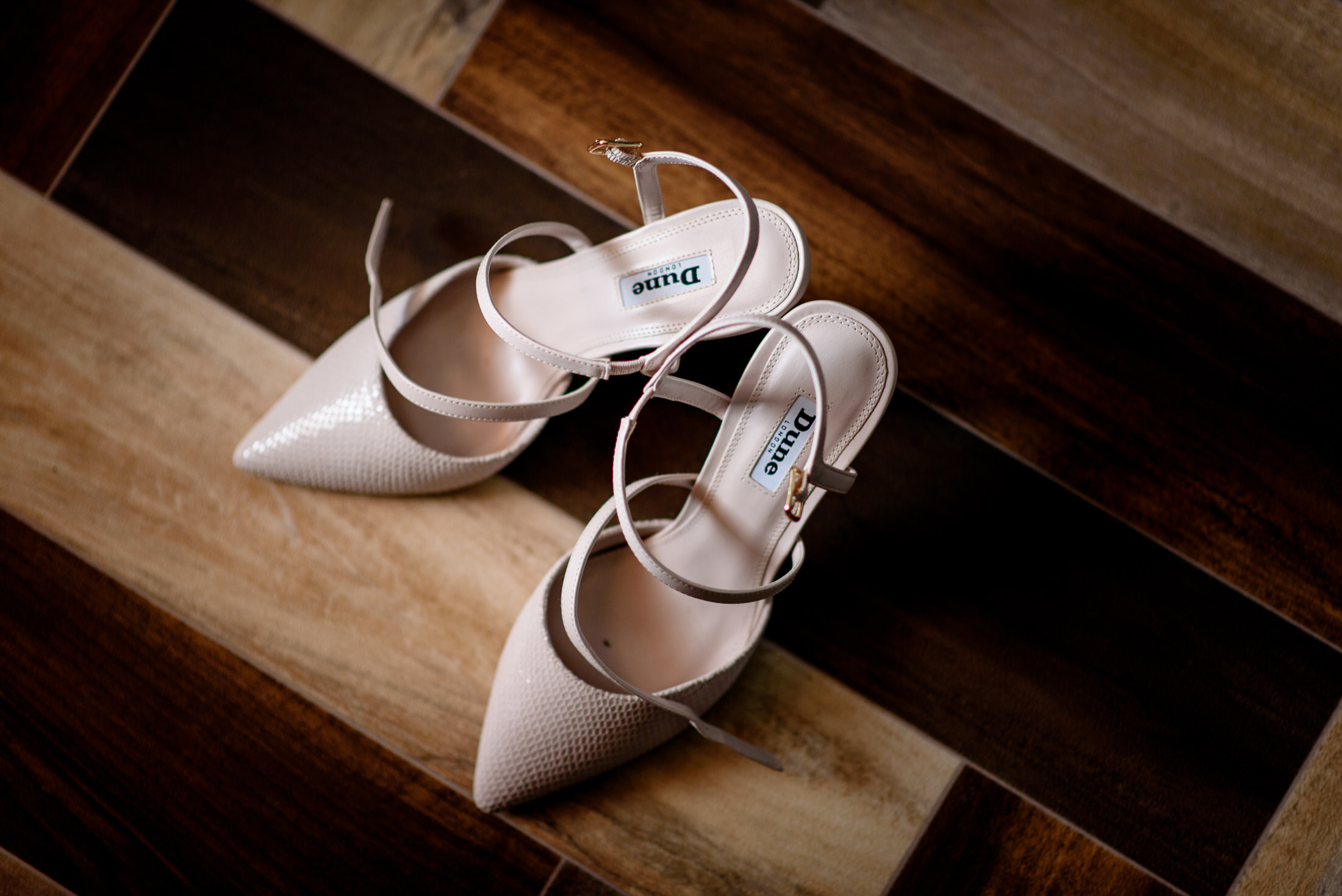 A pair of white wedding shoes on a wooden floor at the Scrivelsby Walled Garden.