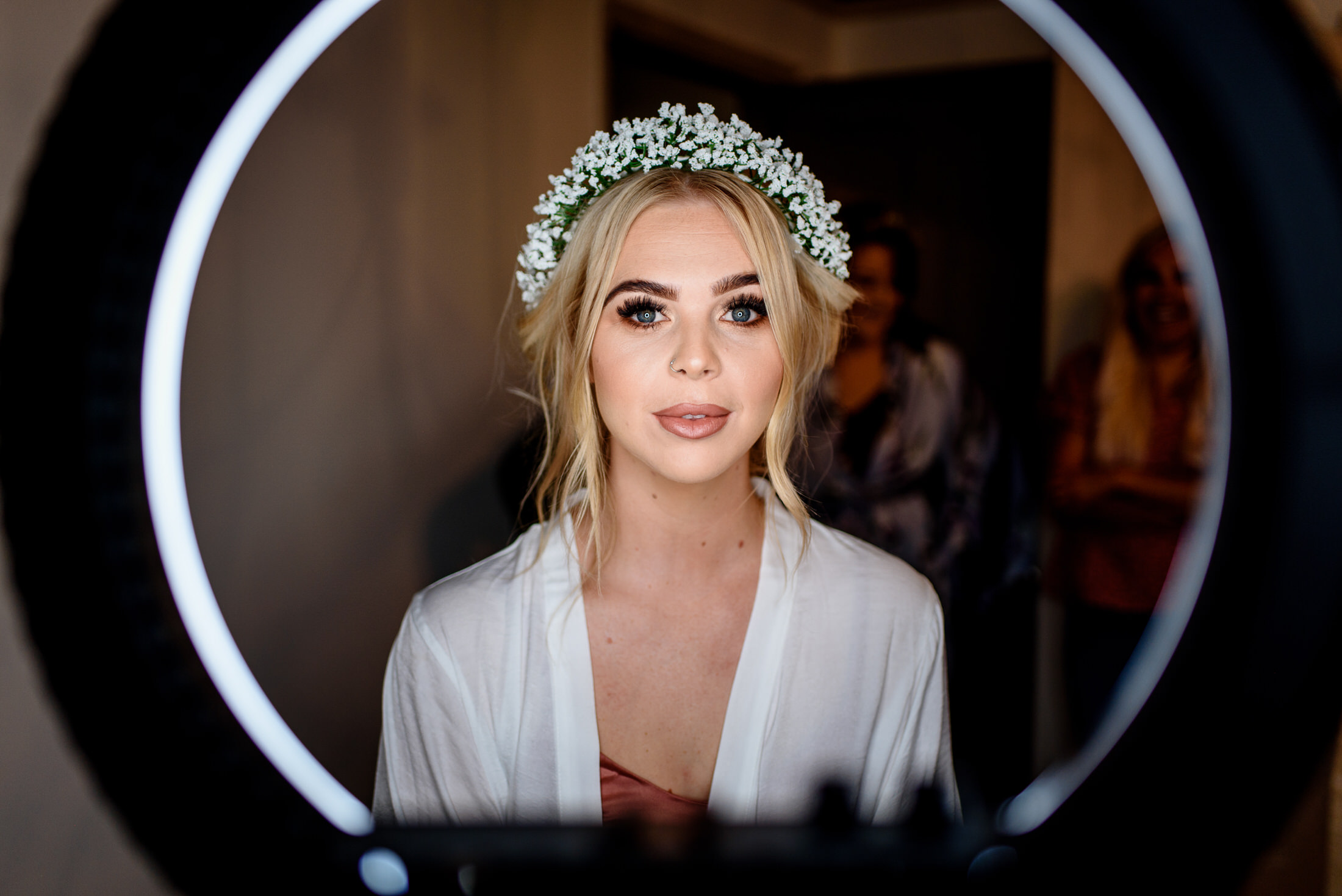 A bride in a wedding dress admiring her reflection in a mirror at Scrivelsby Walled Garden.