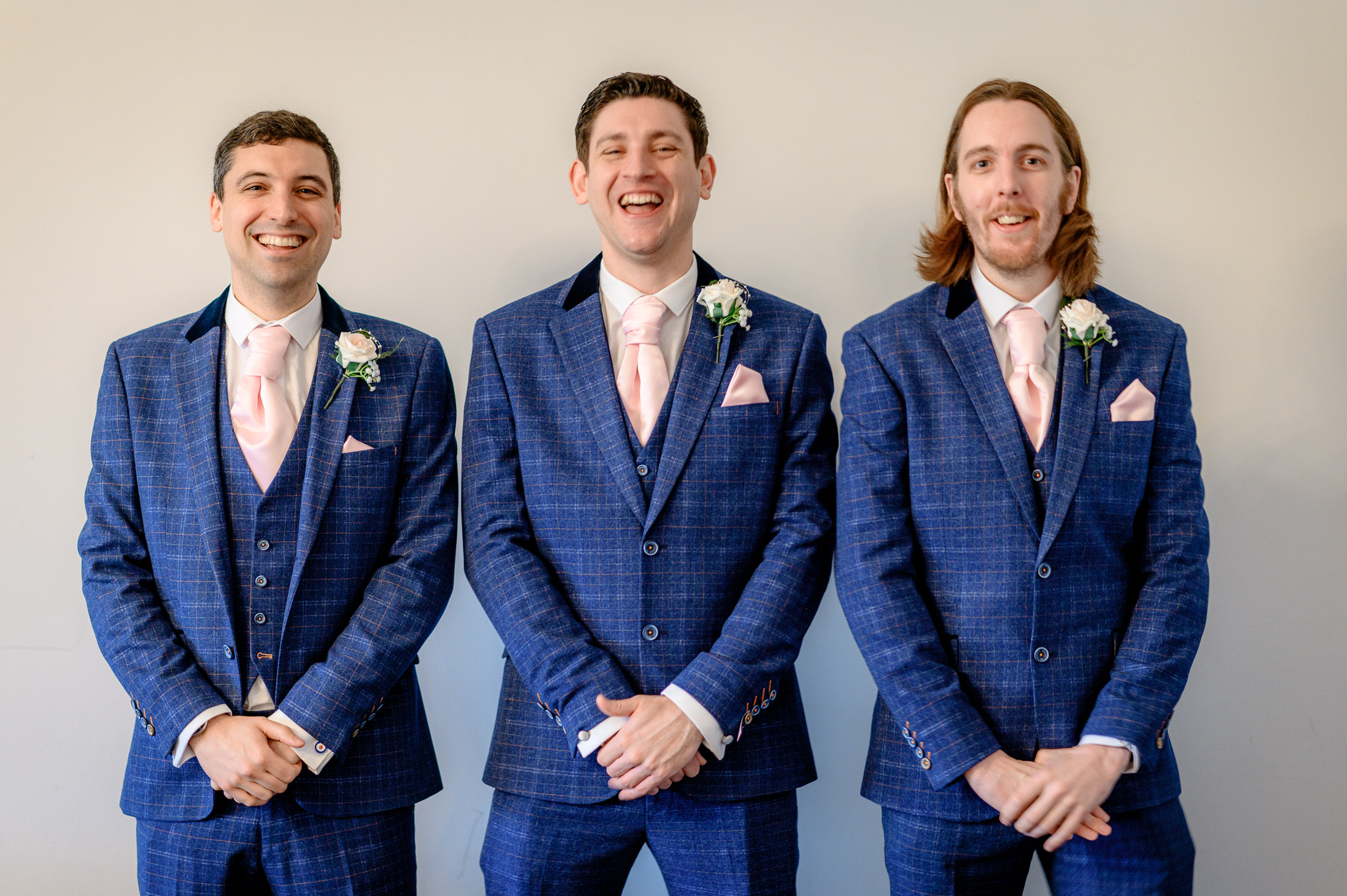 Three groomsmen in blue suits posing for a photo at a wedding at Brackenborough Hotel.