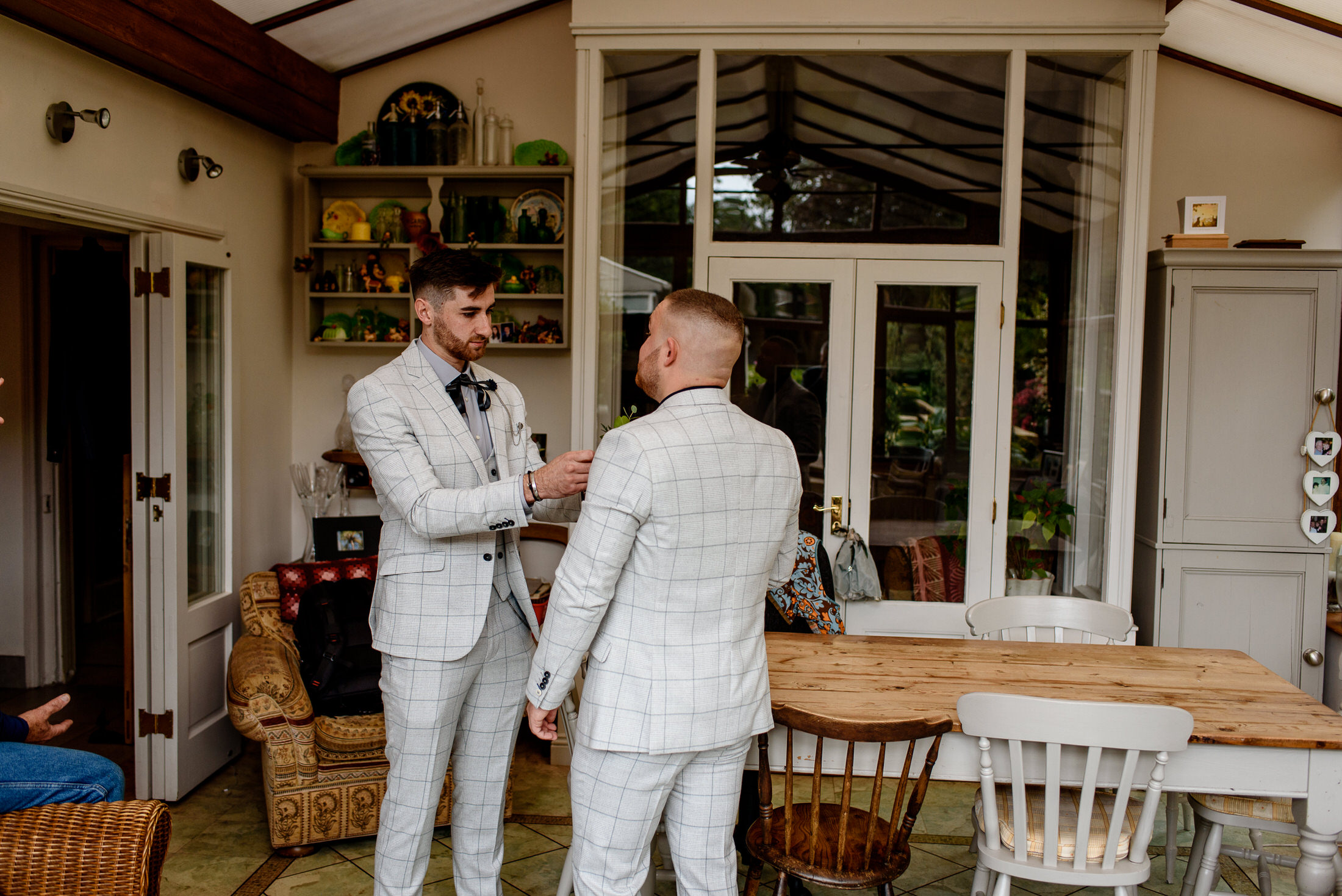 Two men in white suits standing in a wedding venue.