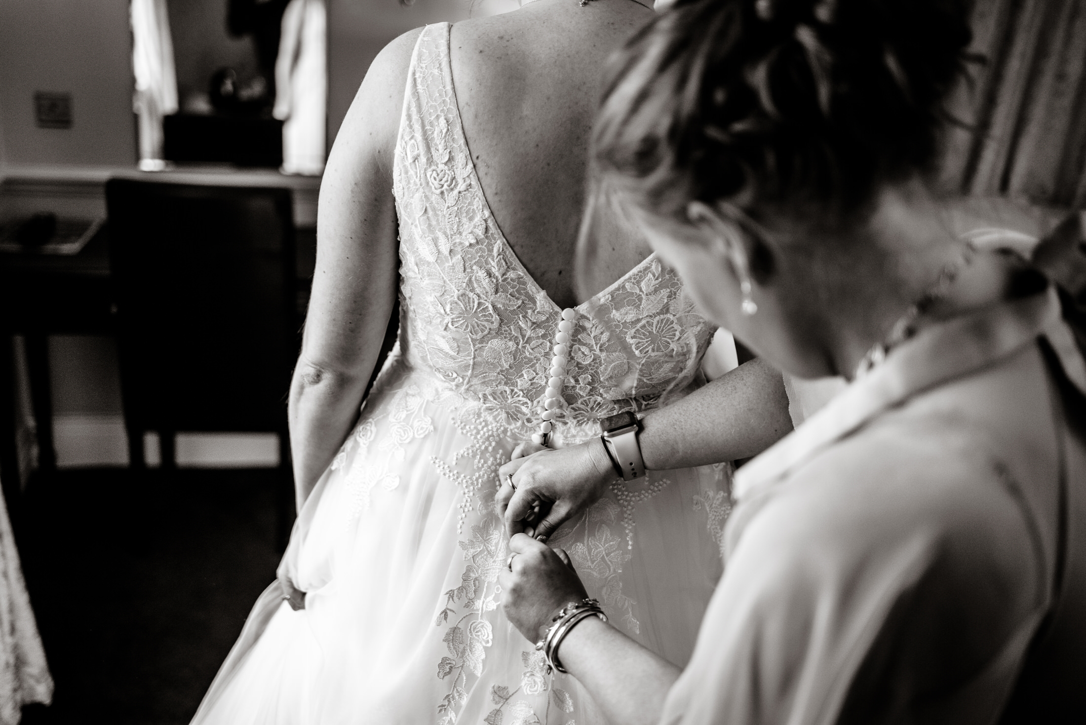 A woman is helping a bride into her wedding dress at the Brackenborough Hotel.