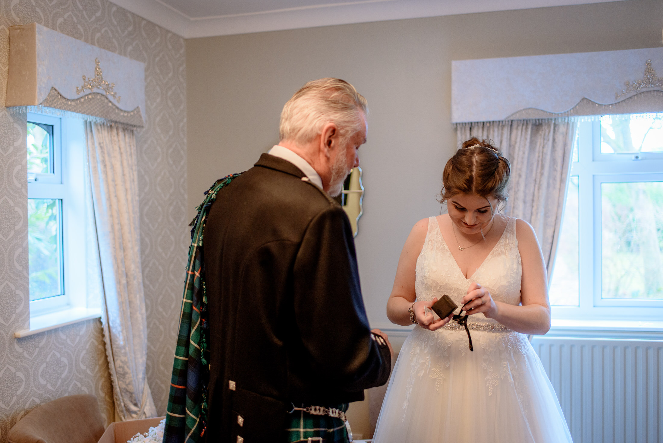 A man at the Brackenborough Hotel is helping a woman put on her wedding dress.
