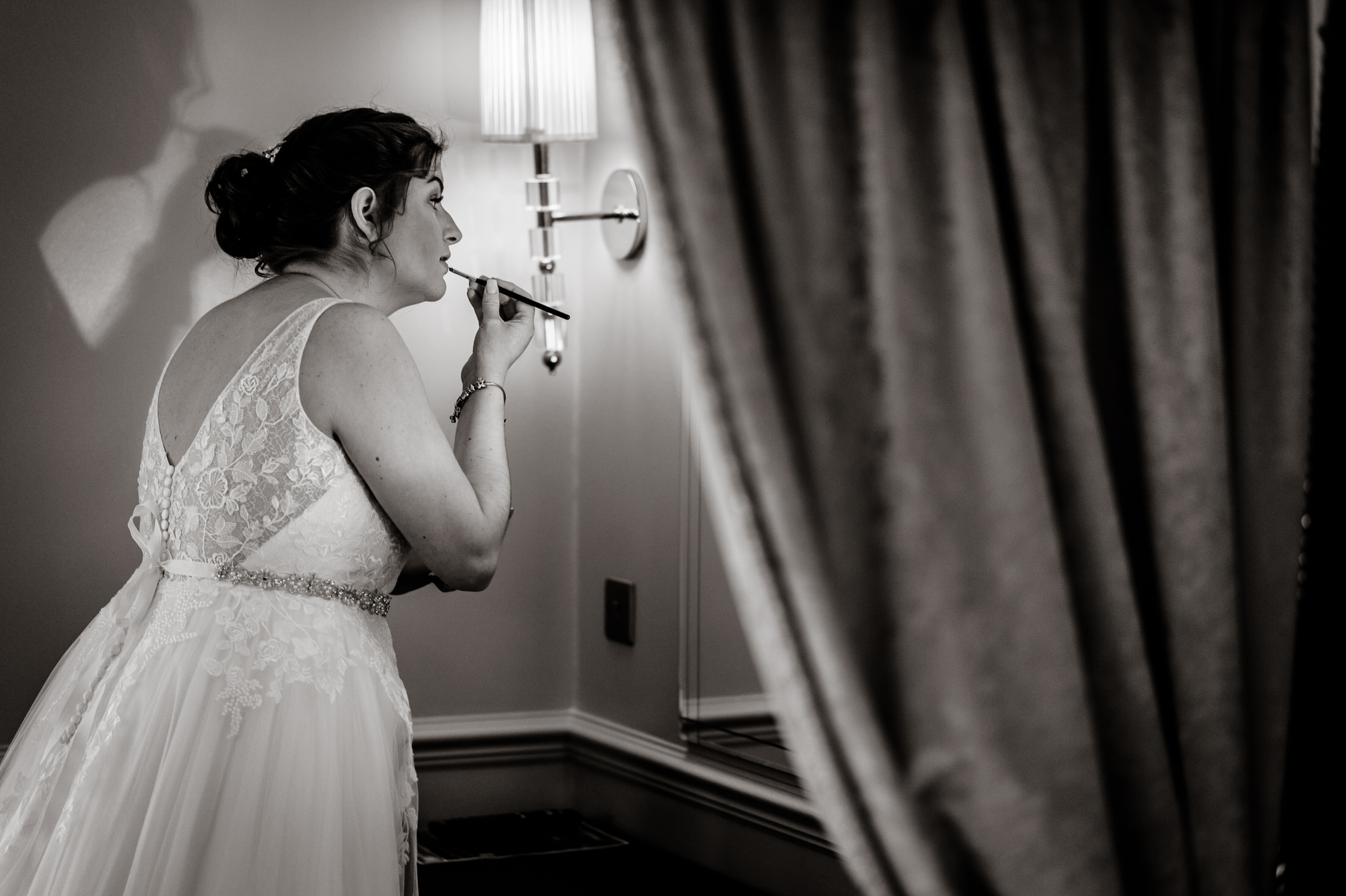 A bride is getting ready in front of a mirror at the Brackenborough Hotel for her wedding.