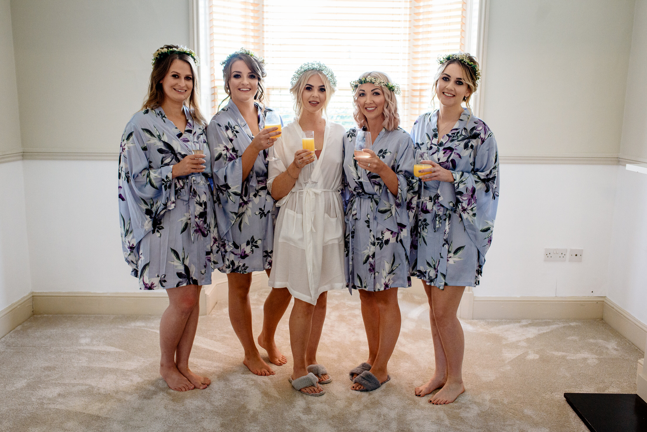 A group of bridesmaids in floral robes posing for a wedding photo.