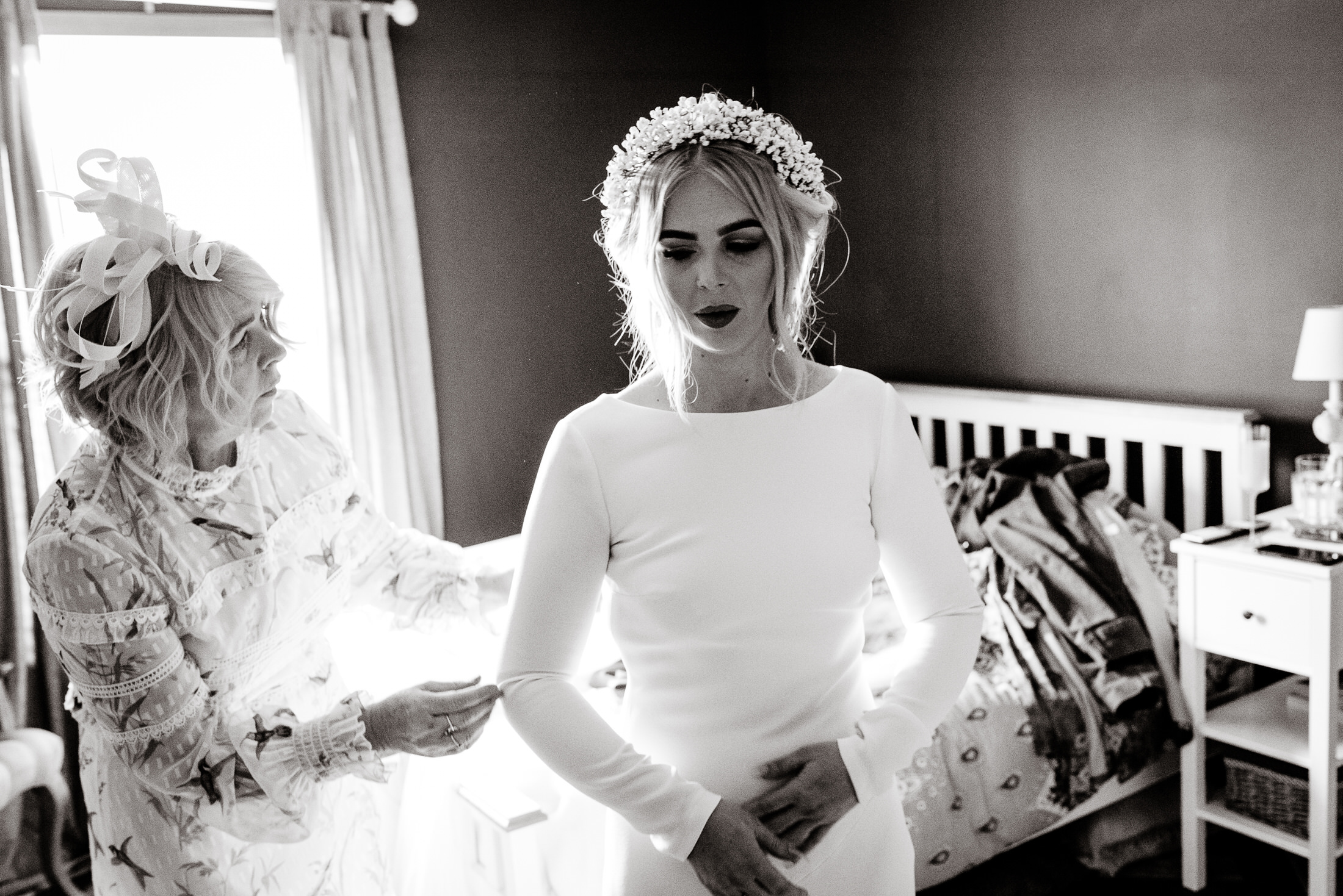 A black and white photo of a wedding bride getting ready in a bedroom at Scrivelsby Walled Garden.