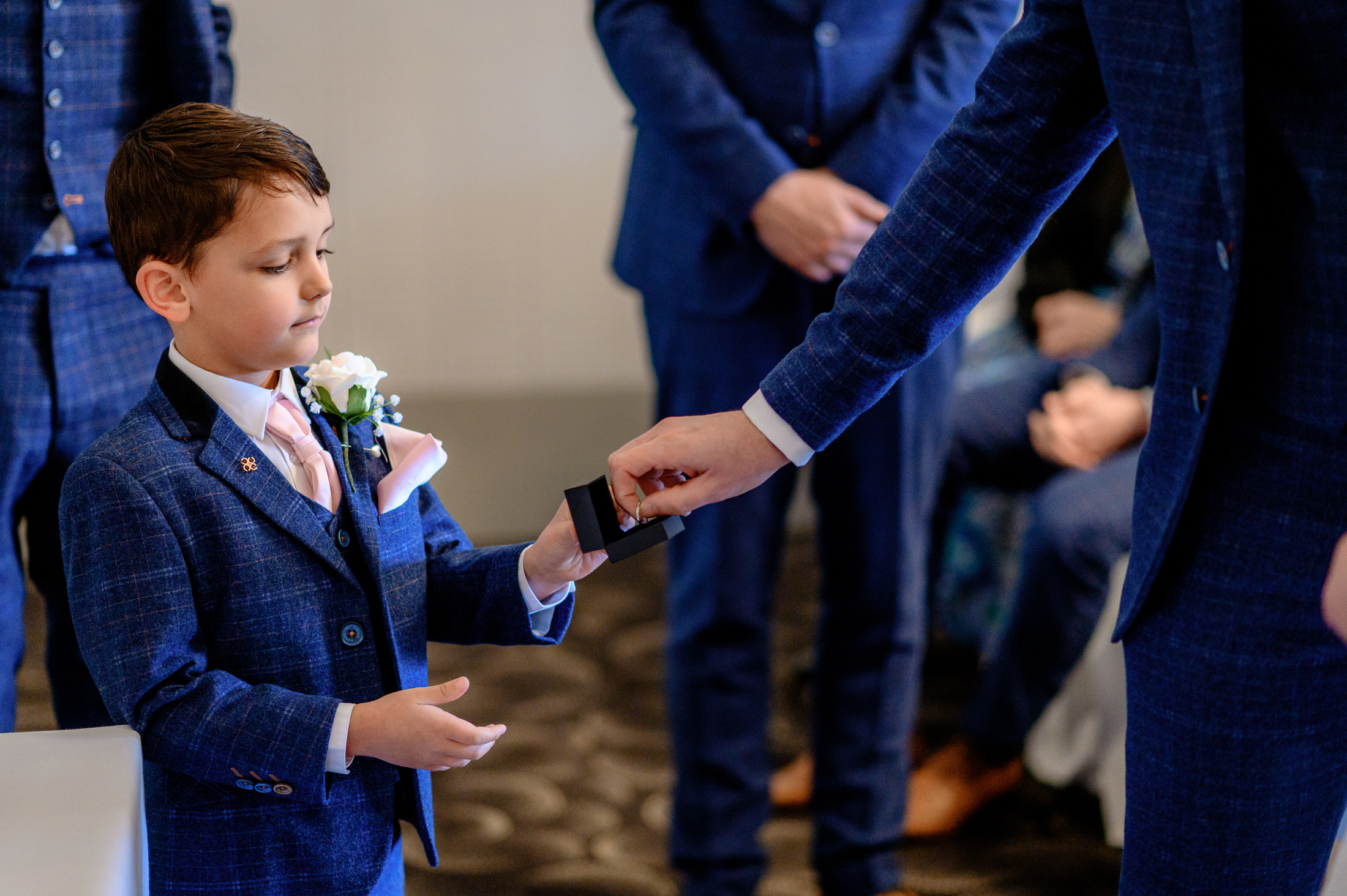 At the elegant Brackenborough Hotel, a young boy in a blue suit is joyfully holding a wedding ring.