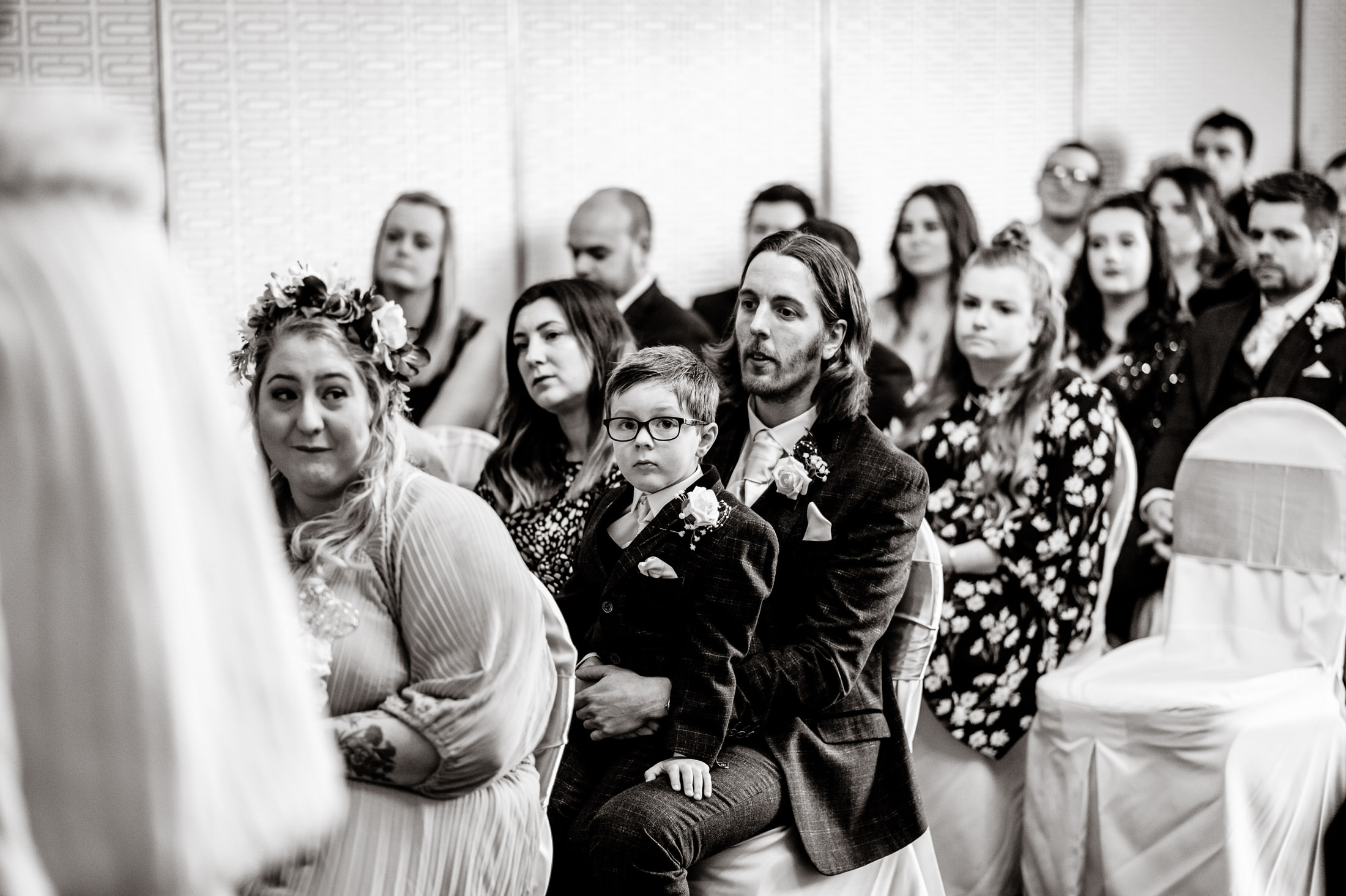 A group of people sitting in chairs at a wedding ceremony at Brackenborough Hotel.