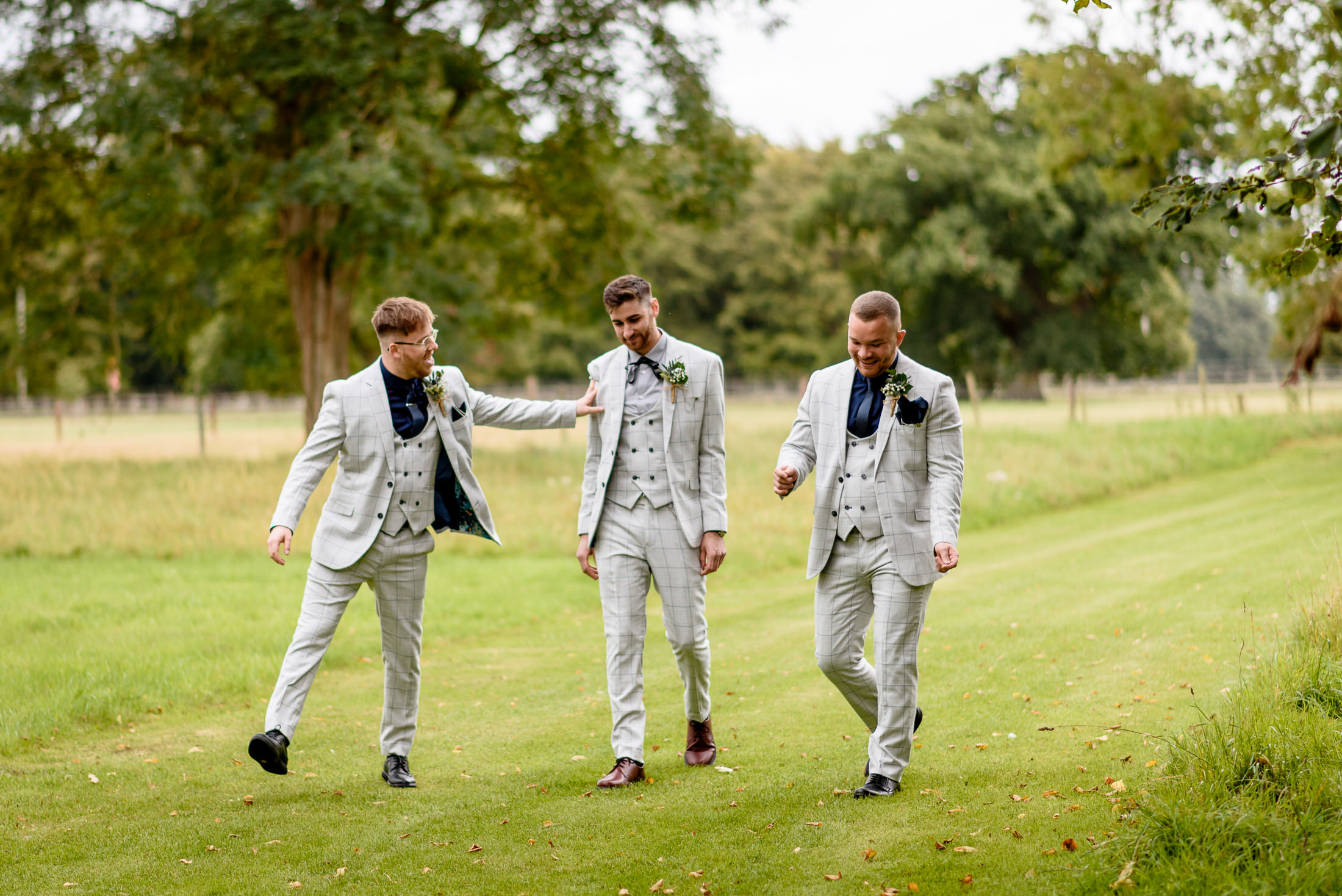 A group of groomsmen walking through a wedding field at Scrivelsby Walled Garden.