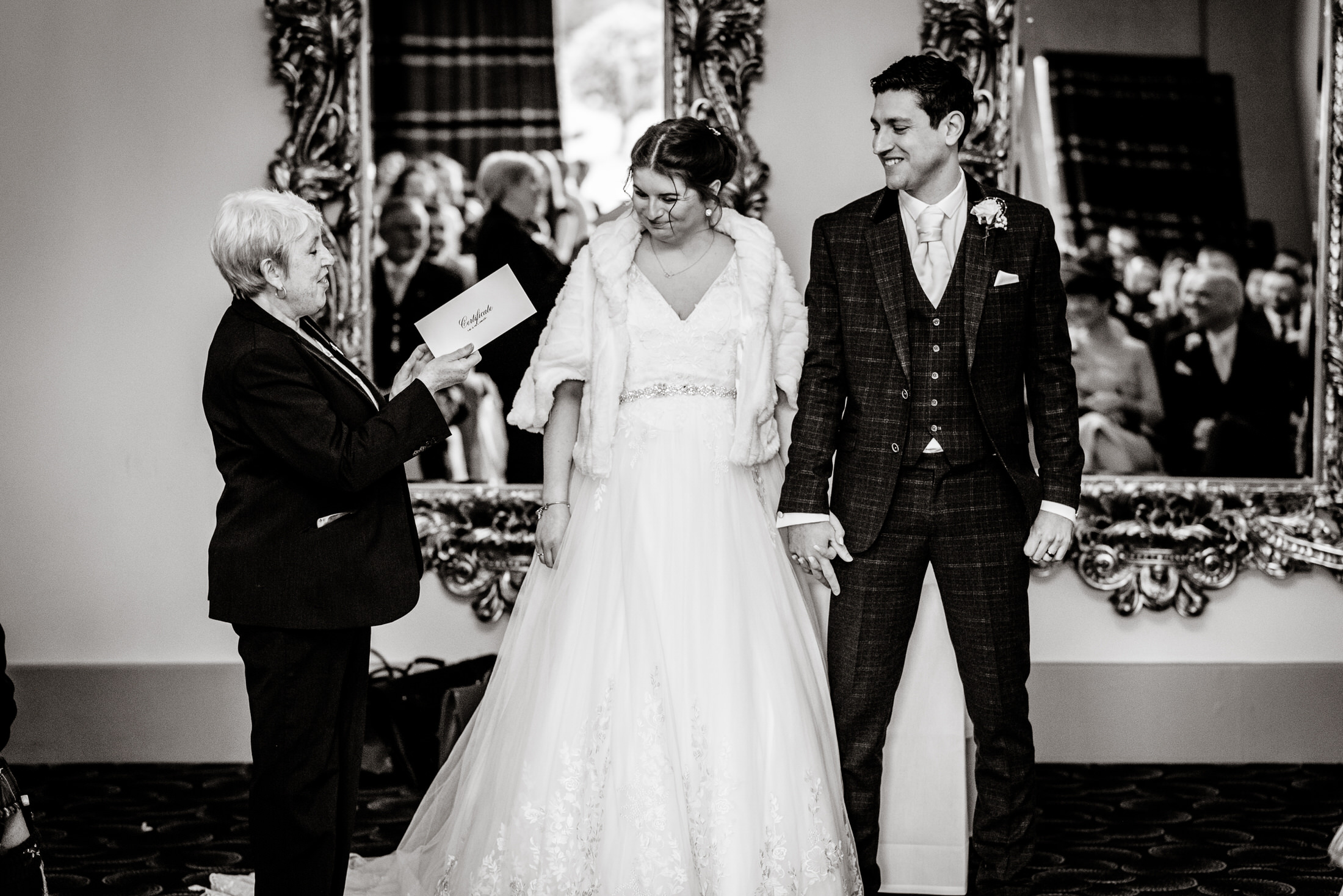 A bride and groom exchange their vows at the Brackenborough Hotel wedding, surrounded by mirrors.