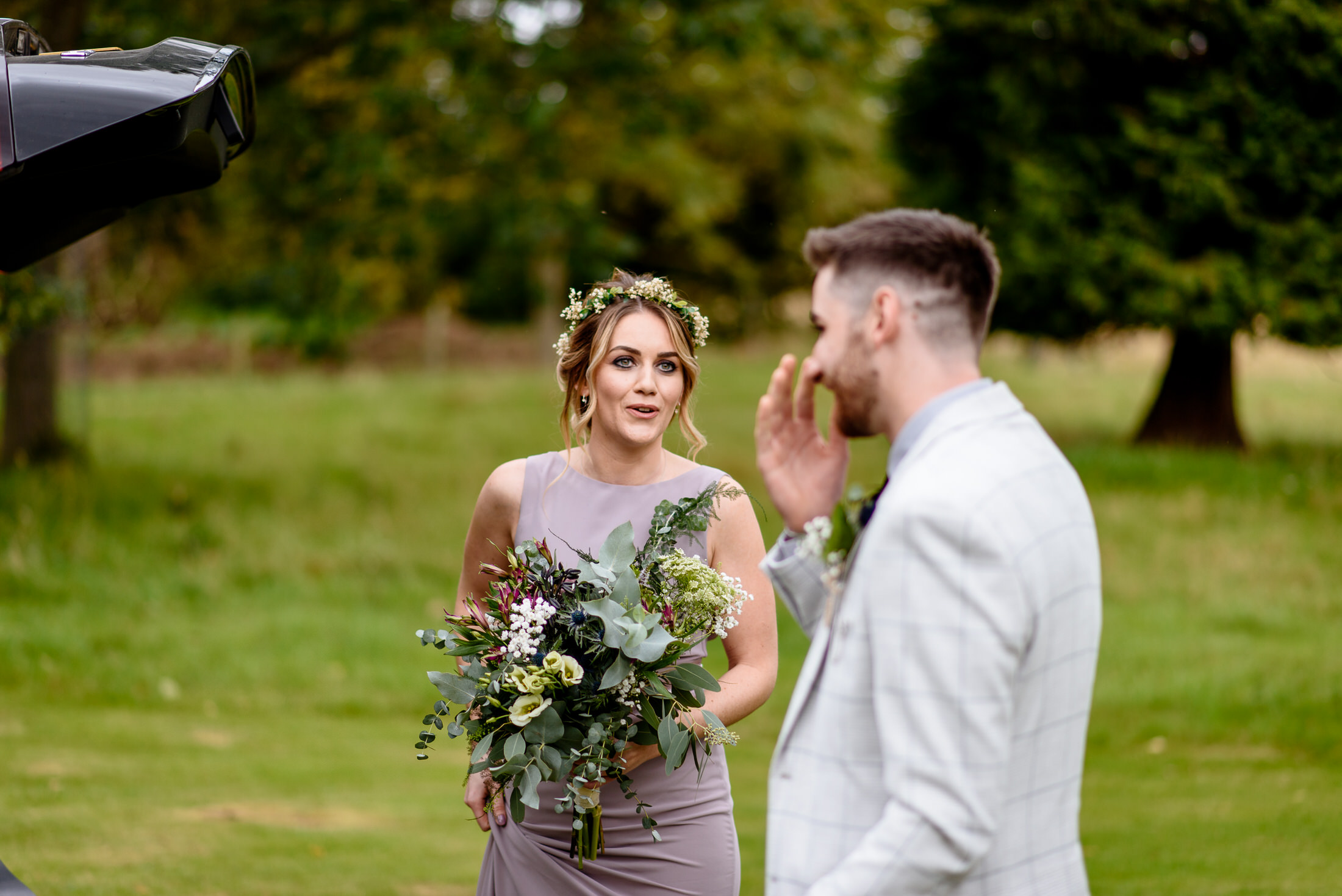 A bride and groom posing next to a car in the picturesque Scrivelsby Walled Garden for their wedding day.