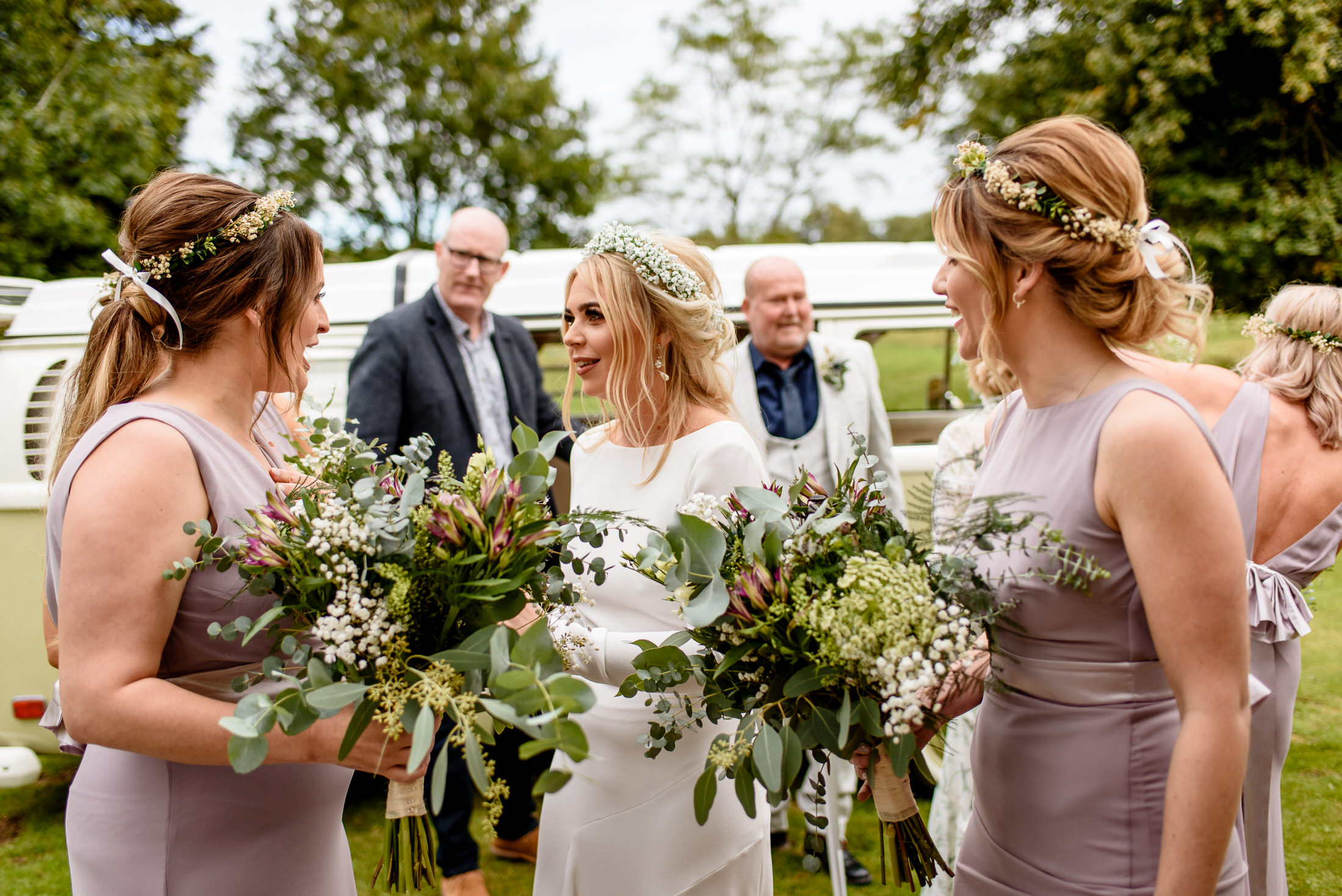 A wedding party, including the bride and her bridesmaids, standing in front of a VW van at Scrivelsby Walled Garden.
