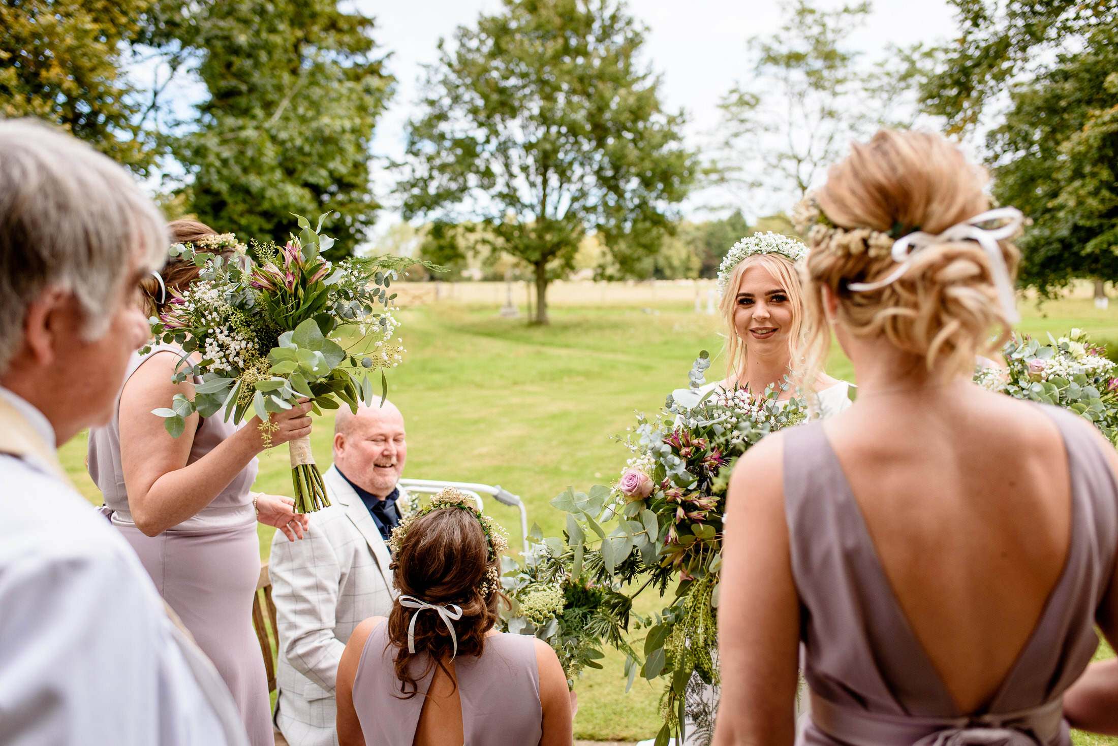 A bride and her bridesmaids look at each other during a wedding ceremony at Scrivelsby Walled Garden.