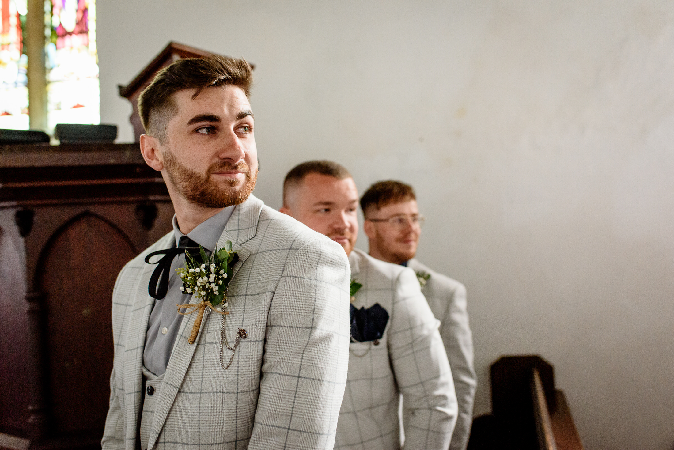 A group of groomsmen standing in a church during a wedding.