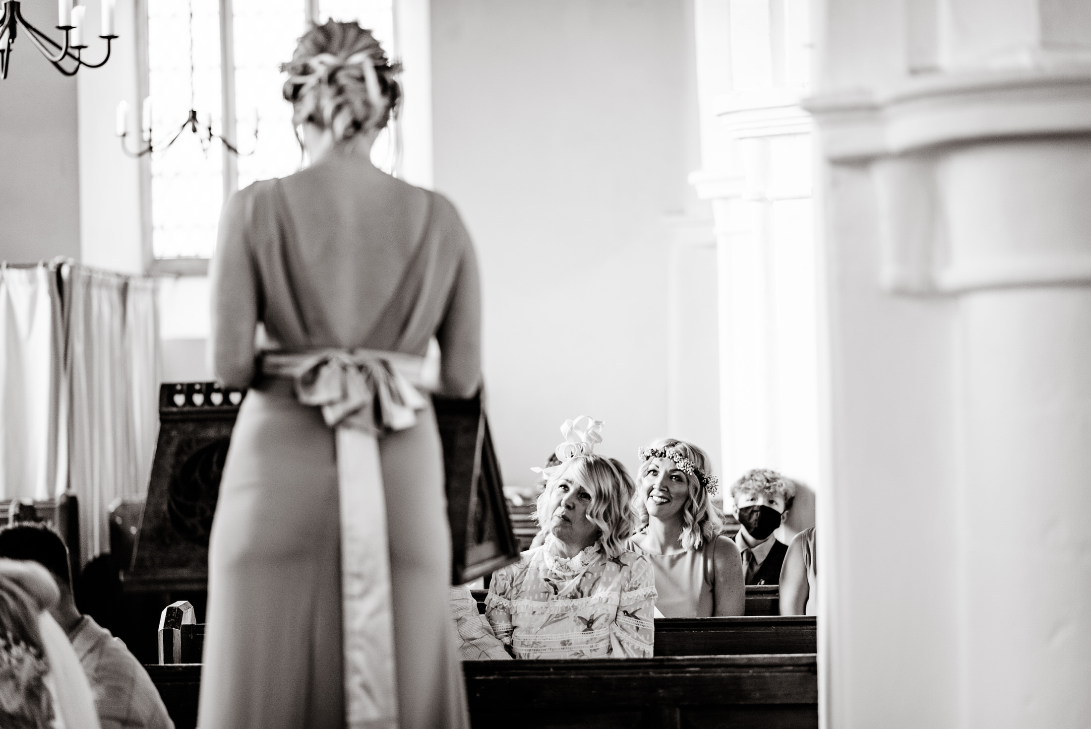 A black and white photo capturing a wedding party, including the bride and bridesmaids, inside a church.