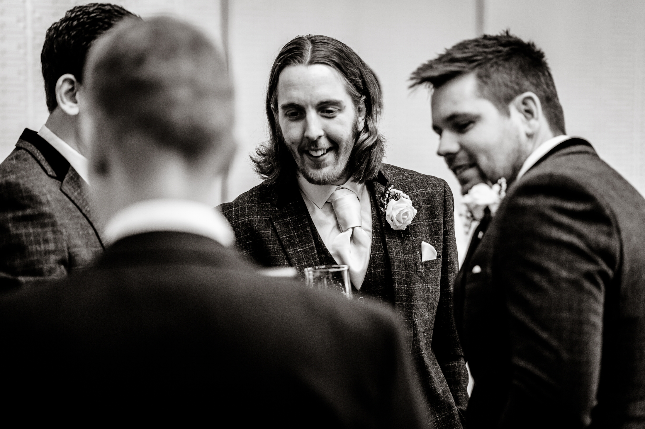 A black and white photo of a group of groomsmen talking at the Brackenborough Hotel wedding.