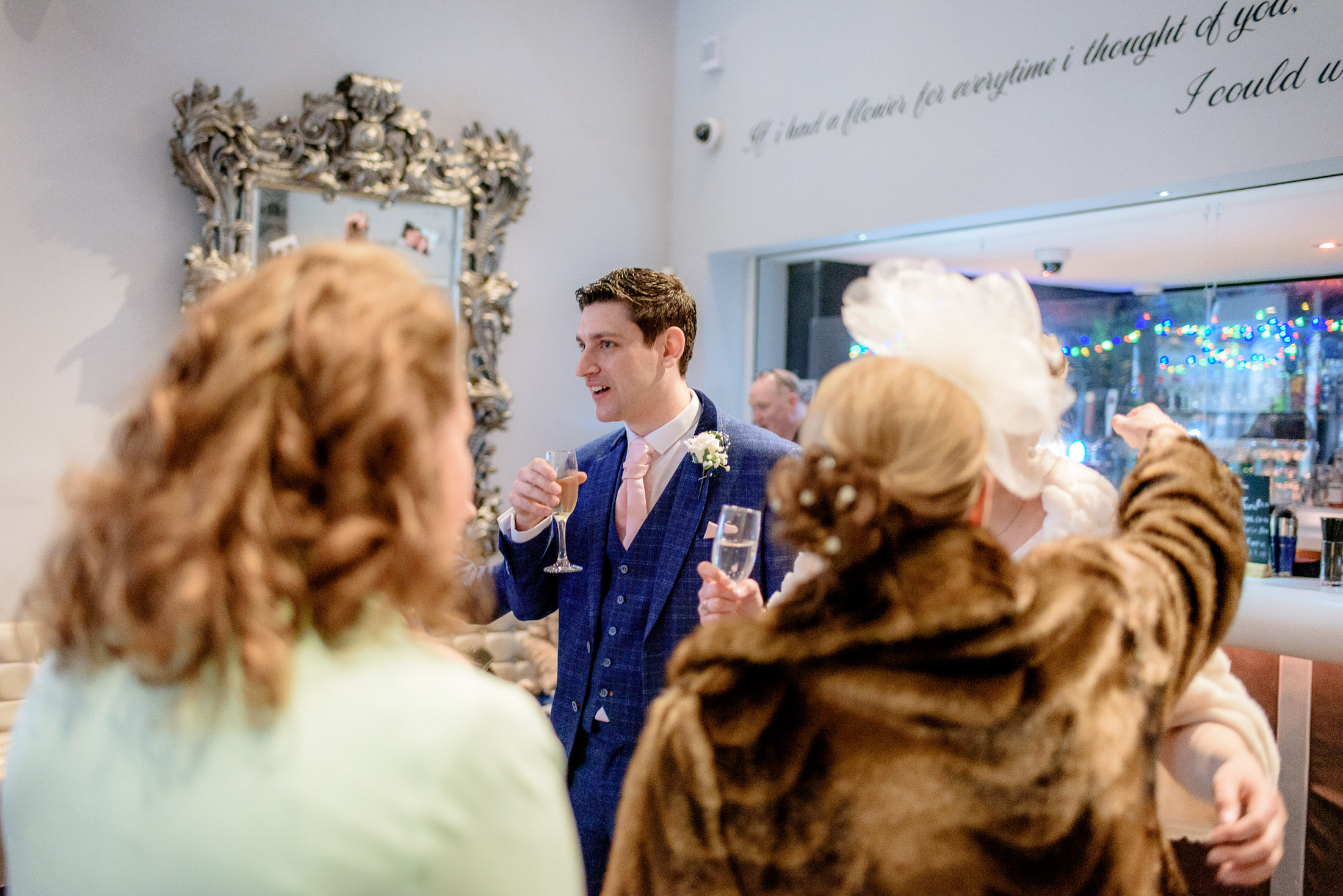 A group of people celebrating a wedding at the Brackenborough Hotel, sipping champagne in a room.