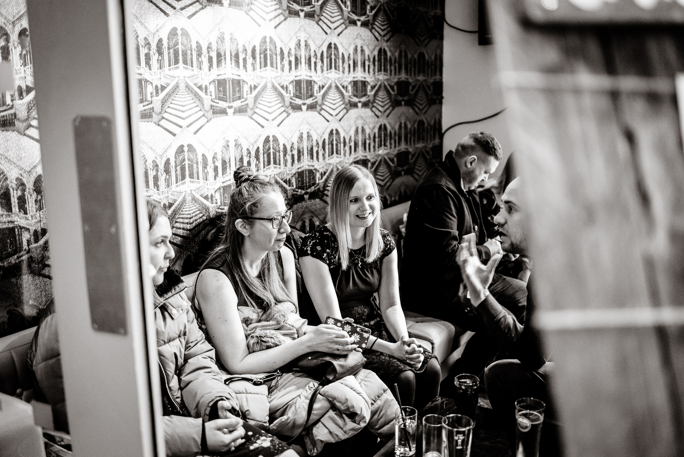 A group of people sitting on a couch watching TV at the Brackenborough Hotel wedding.