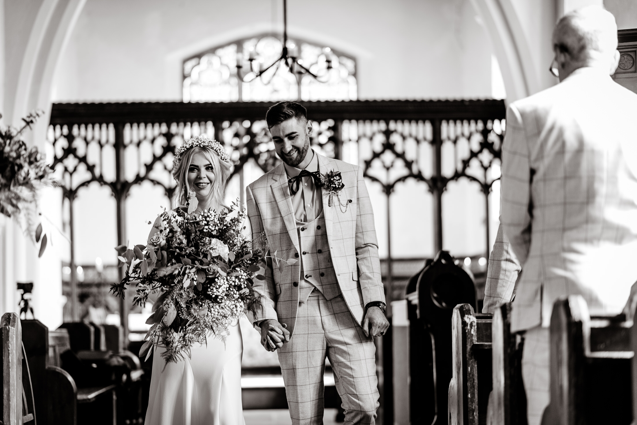 A wedding couple gracefully walking down the aisle of a church.