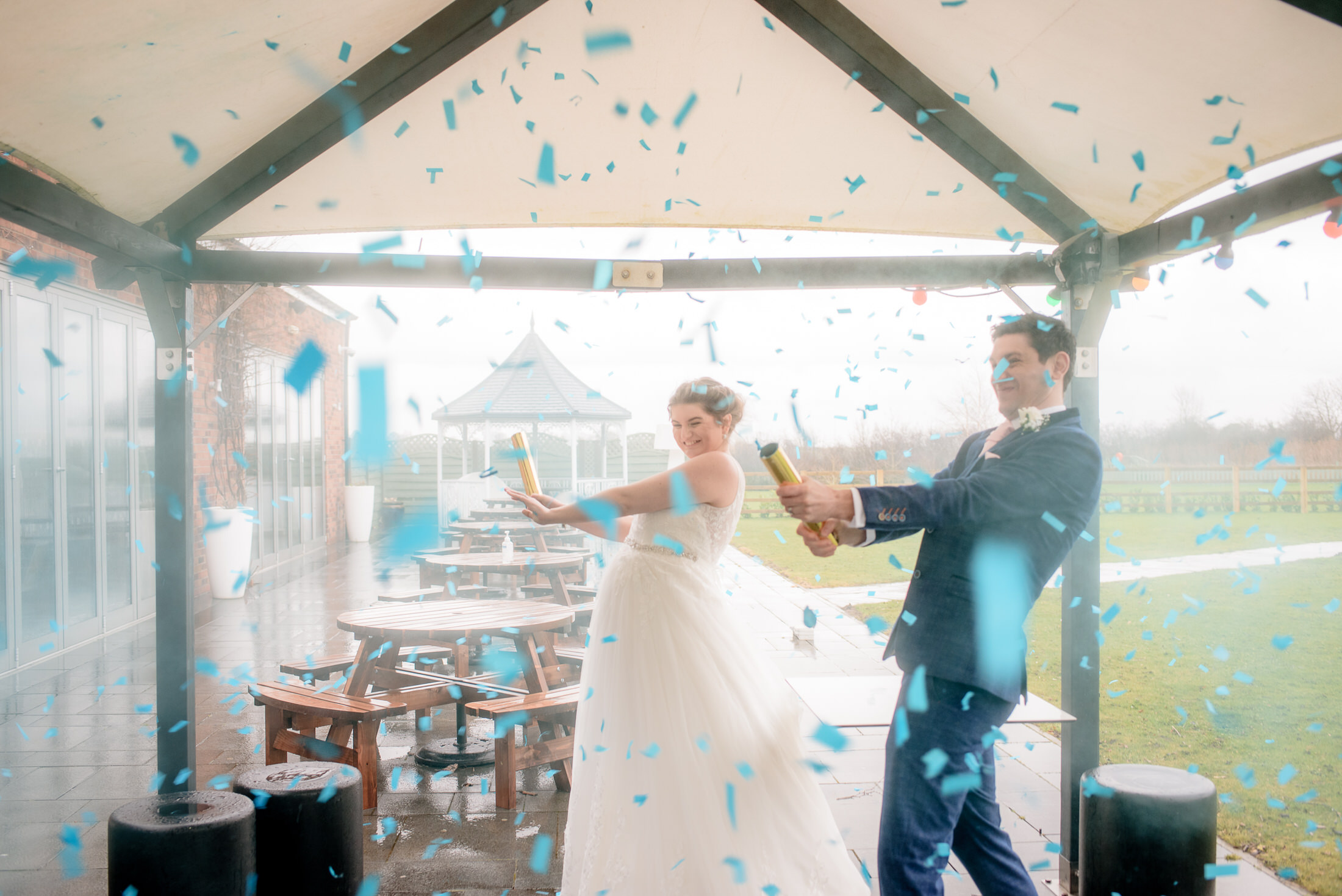 A couple celebrating their wedding at the Brackenborough Hotel, joyfully throwing confetti at each other.