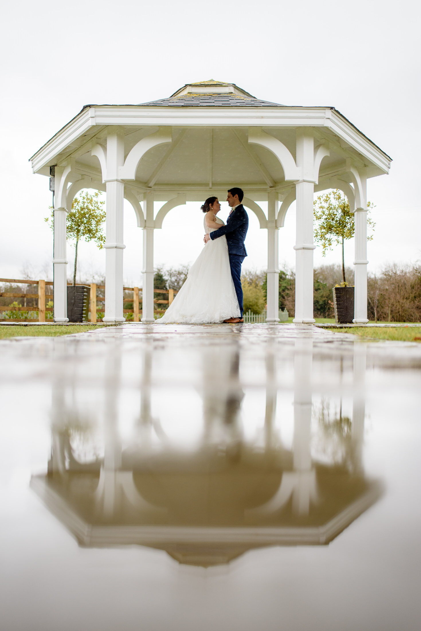A bride and groom standing under a gazebo in the rain at their Brackenborough Hotel wedding.