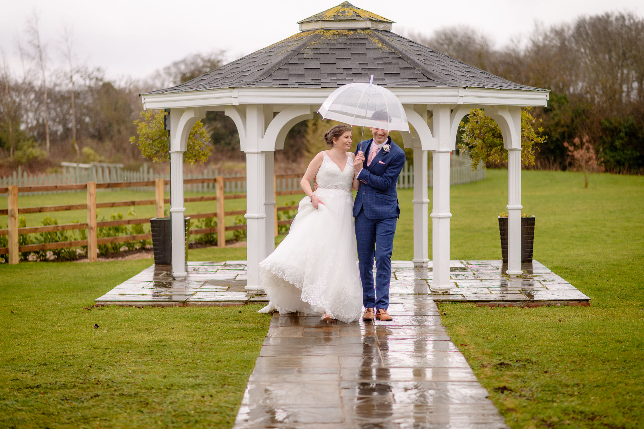 A memorable wedding at the Brackenborough Hotel, with the bride and groom holding an umbrella in the rain.