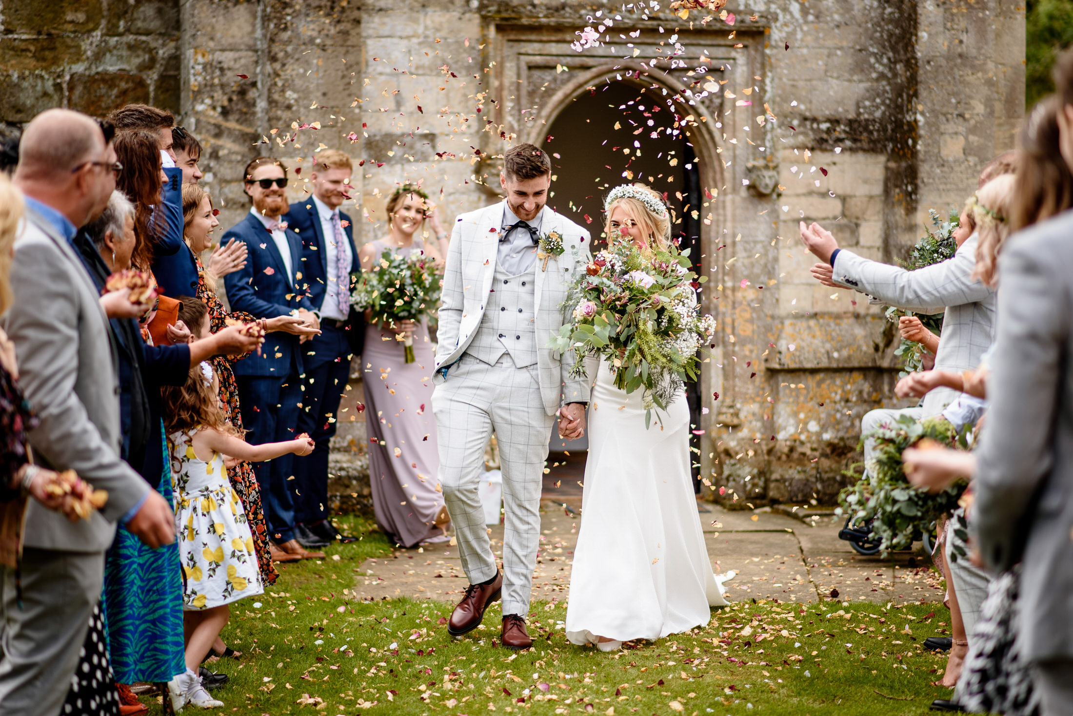 A wedding couple walks down the aisle surrounded by confetti at Scrivelsby Walled Garden.