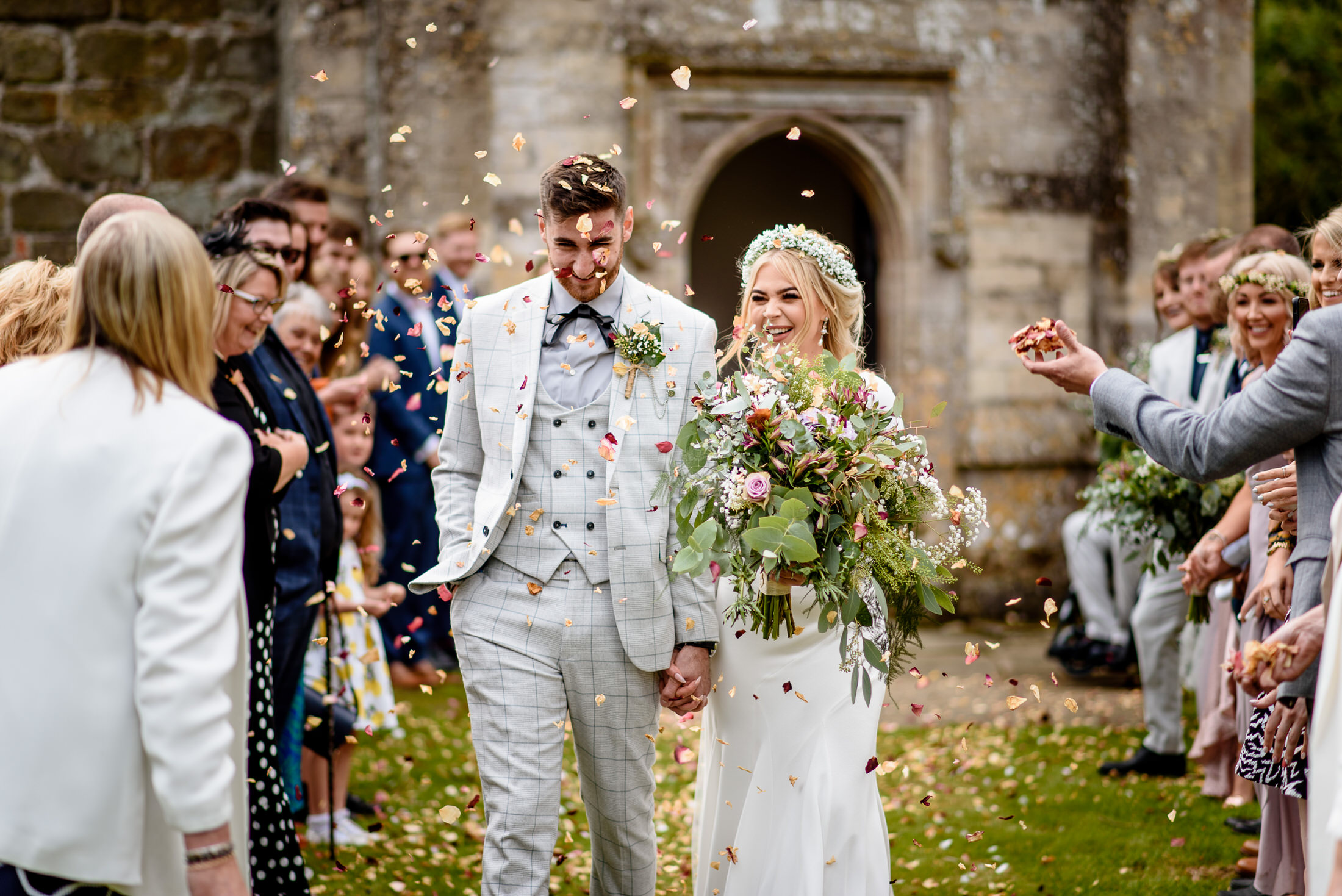 A wedding couple walking down the aisle at Scrivelsby Walled Garden, with confetti thrown at them.