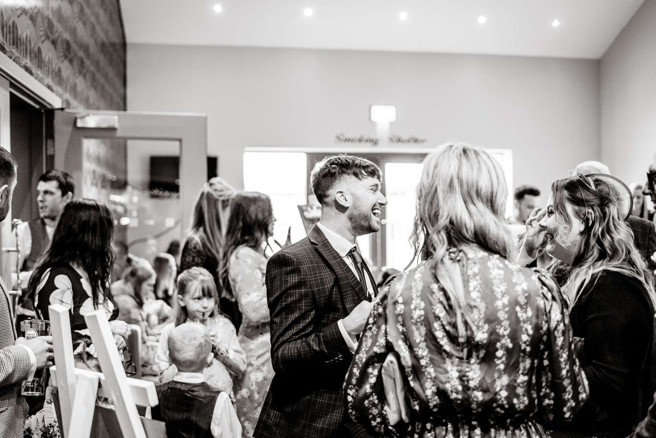 A man in a suit and tie standing in front of a group of people at the Brackenborough Hotel wedding.