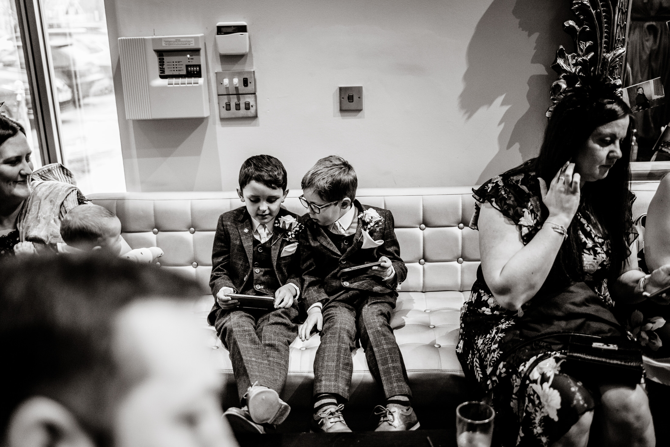 A group of people sitting on a couch at the Brackenborough Hotel wedding, captured in a black and white photo.