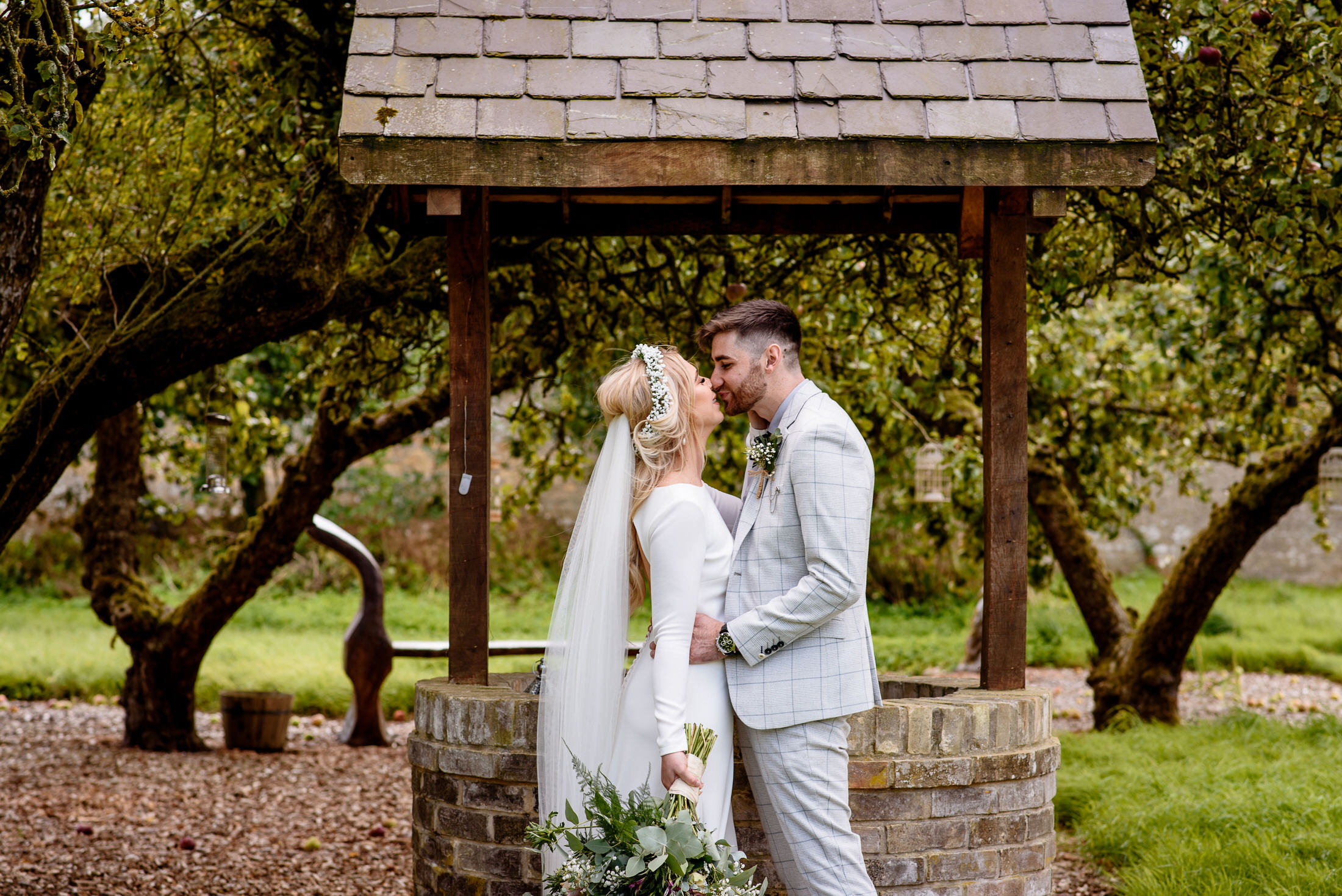 A wedding couple kiss in front of a gazebo at the Scrivelsby Walled Garden.