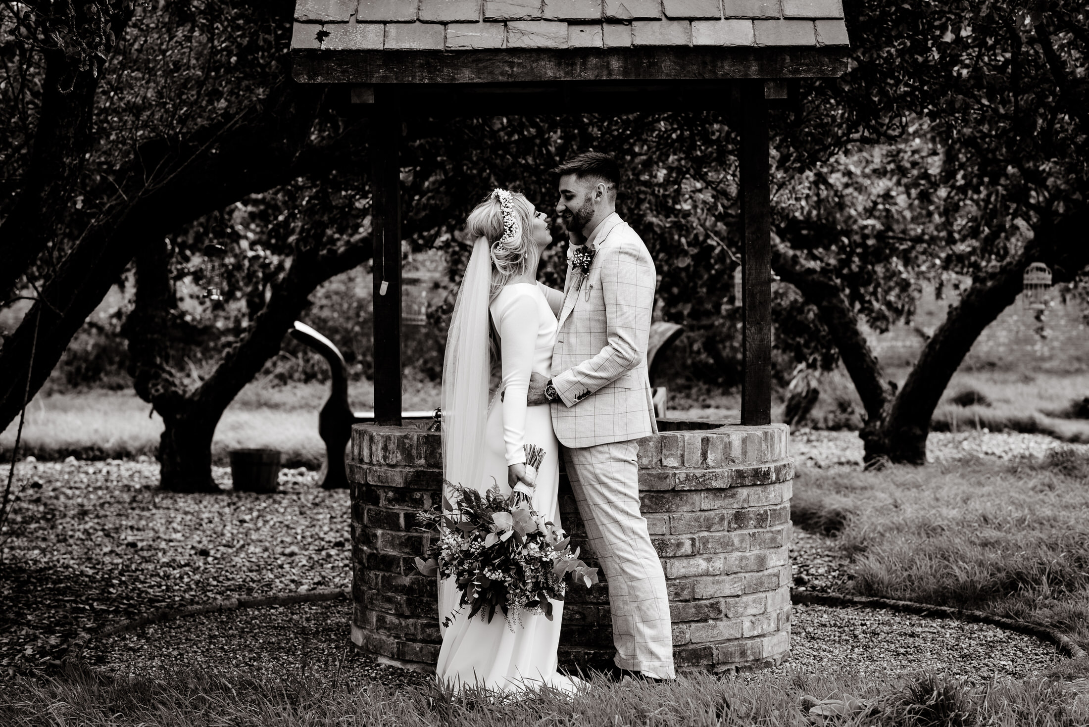 A bride and groom share a romantic kiss amidst the enchanting ambience of the Scrivelsby Walled Garden on their wedding day.