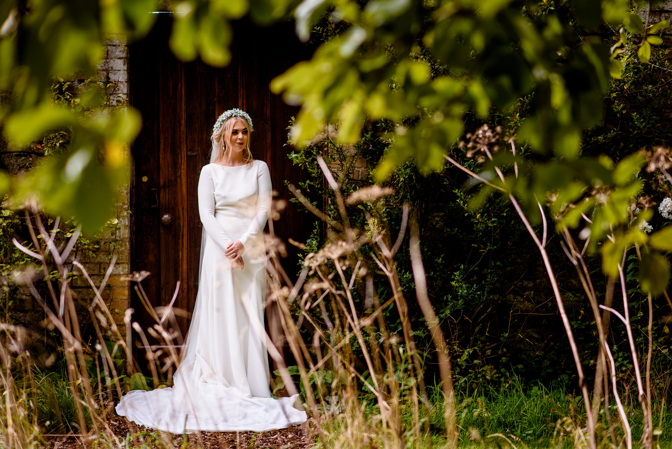 A wedding bride in a white dress standing in tall grass at Scrivelsby Walled Garden.