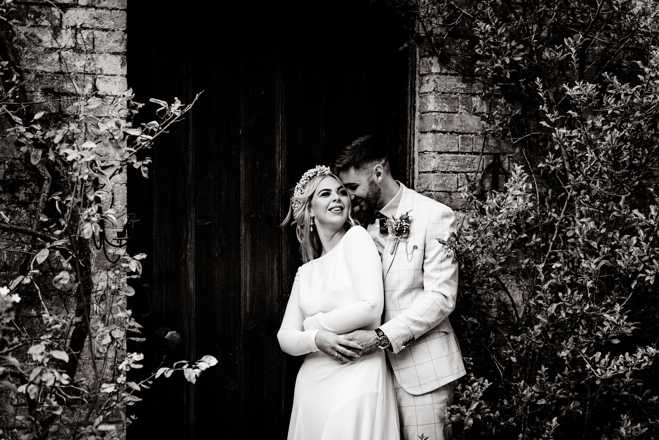 A wedding couple embracing in front of the door at Scrivelsby Walled Garden.